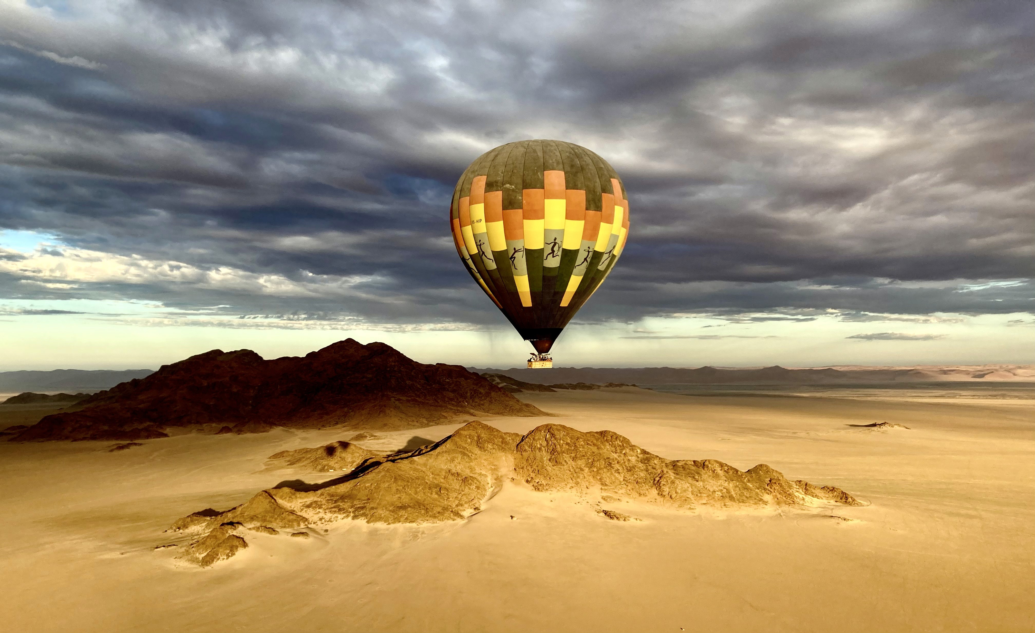 Solitary traveler walking across golden sand dunes at sunrise, with intricate wind-sculpted patterns and a warm, glowing horizon in the Namib Desert.