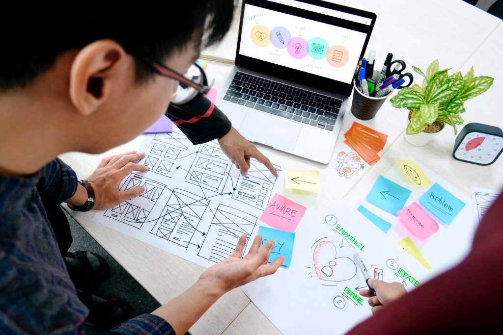 Team sketching wireframes with sticky notes and a laptop to improve the user experience