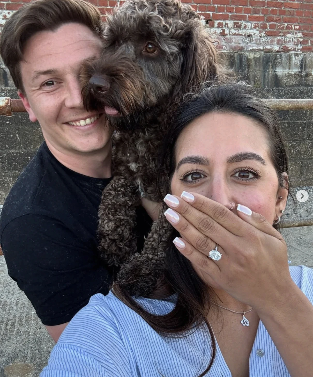 Connor and Cherine with their dog, showing off an engagement ring