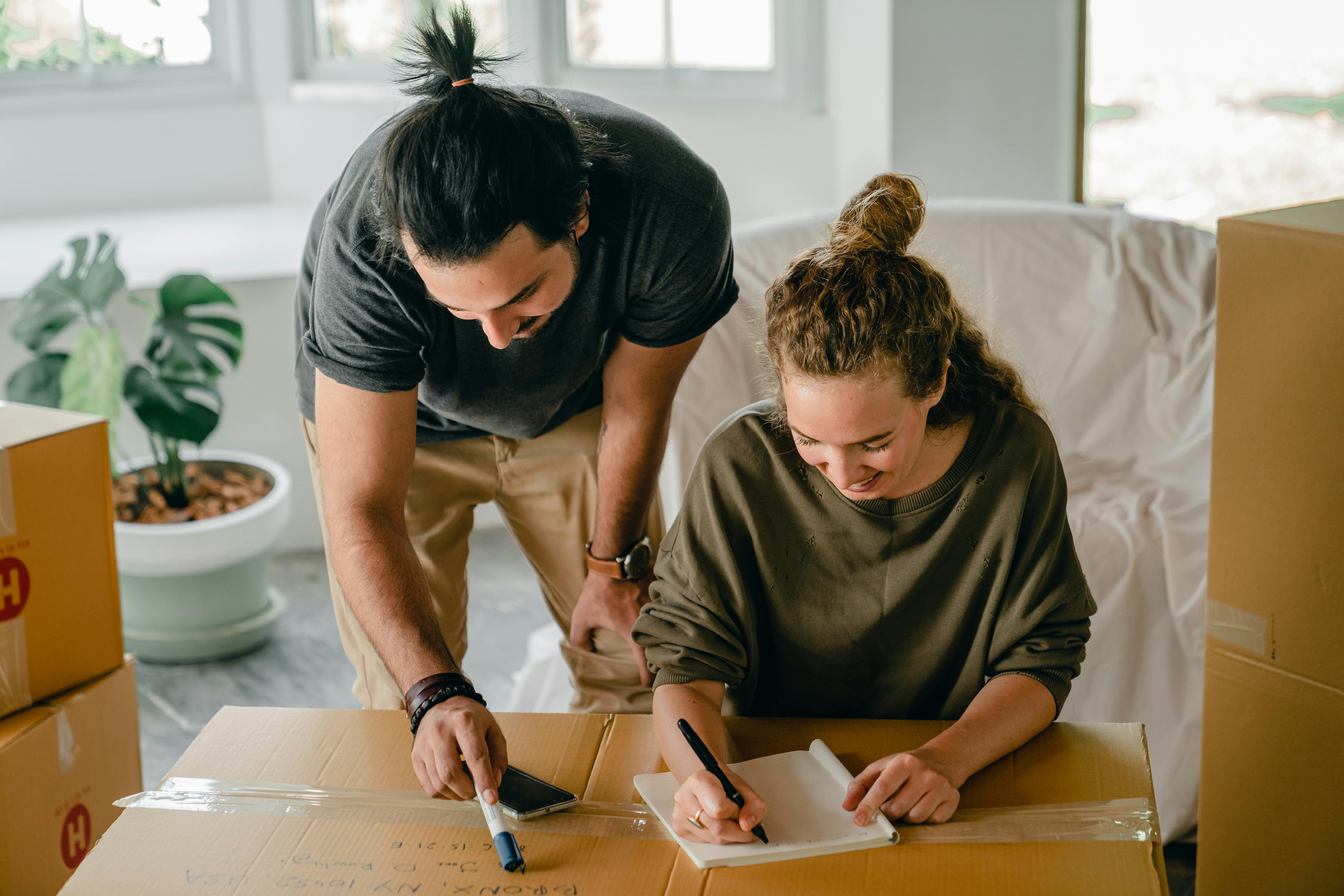 Young couple completing checklist amongst house moving boxes