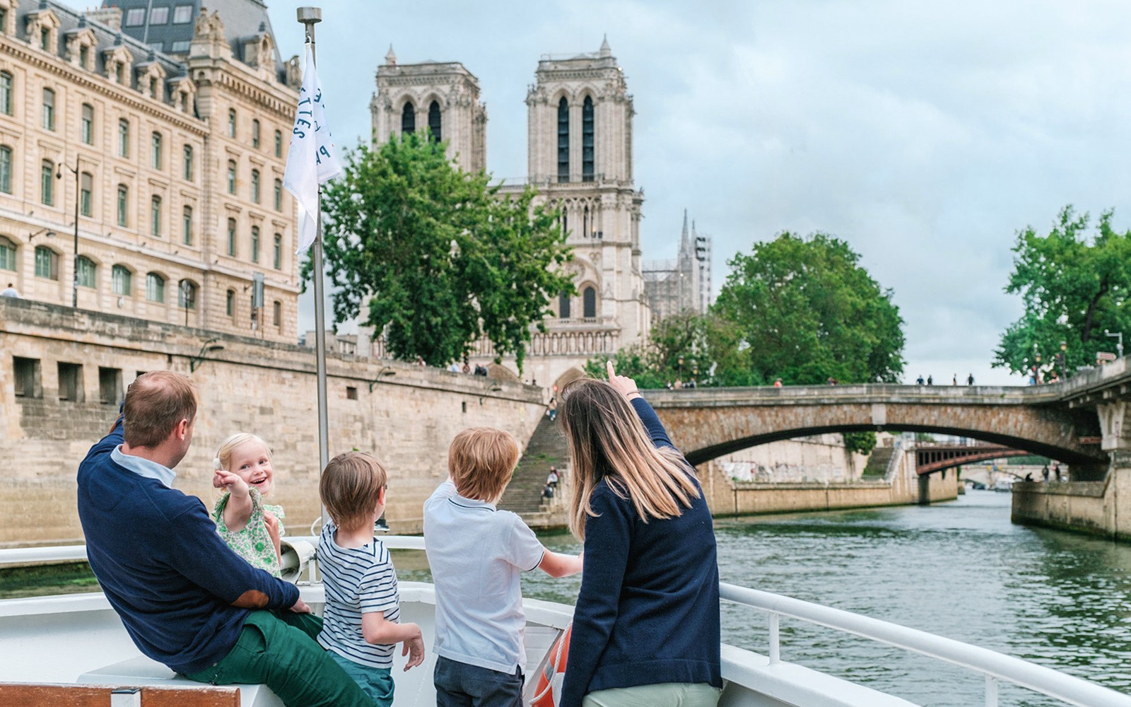 Familie nyder en Seine-flodkrydstogt med udsigt til Notre-Dame-katedralen i Paris.
