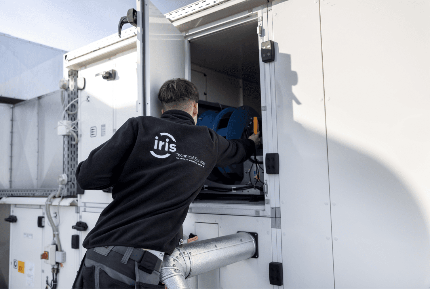 Employee of Iris Technical Services working inside a cabinet
