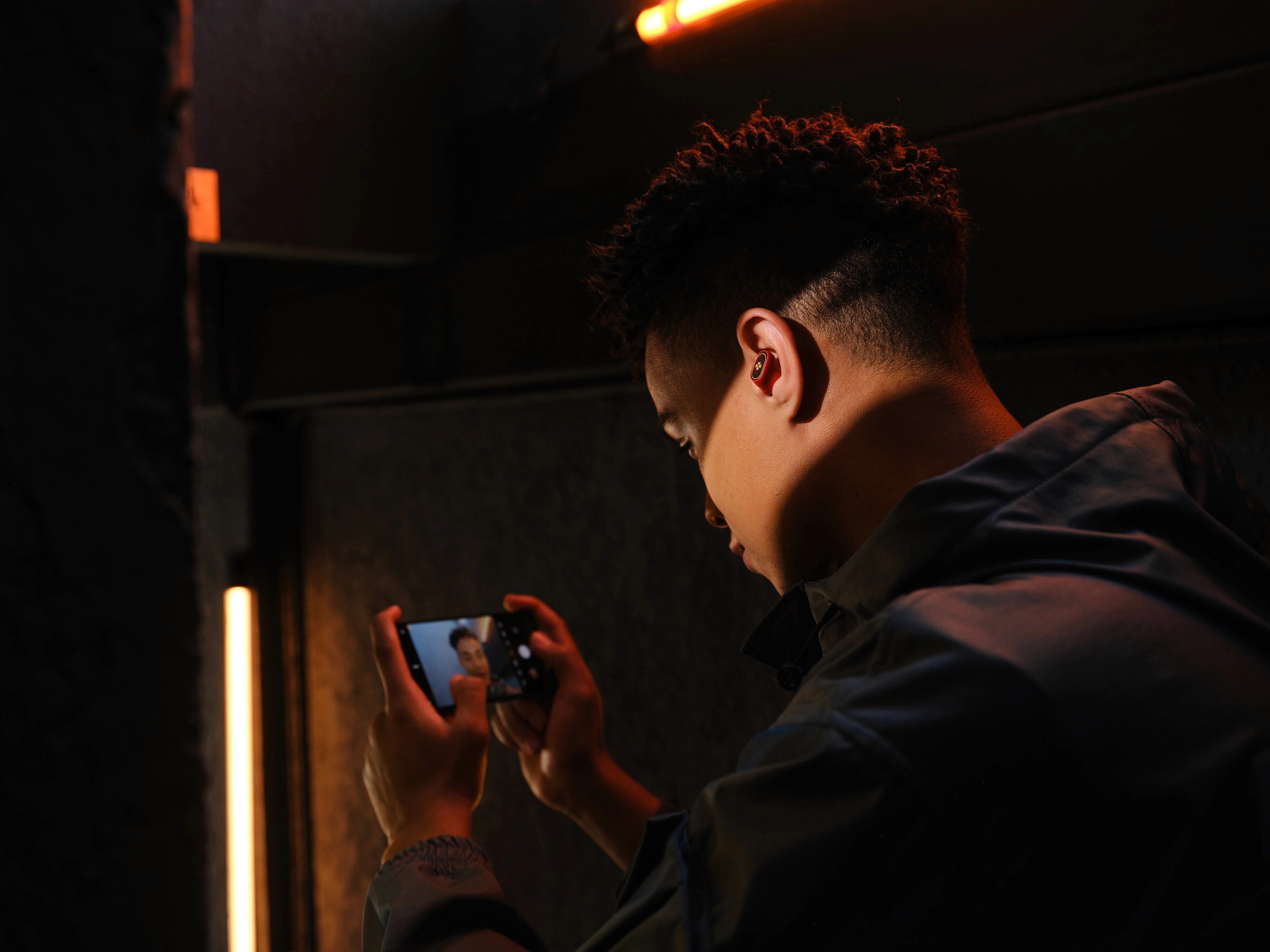 person playing game on phone while wearing earbuds