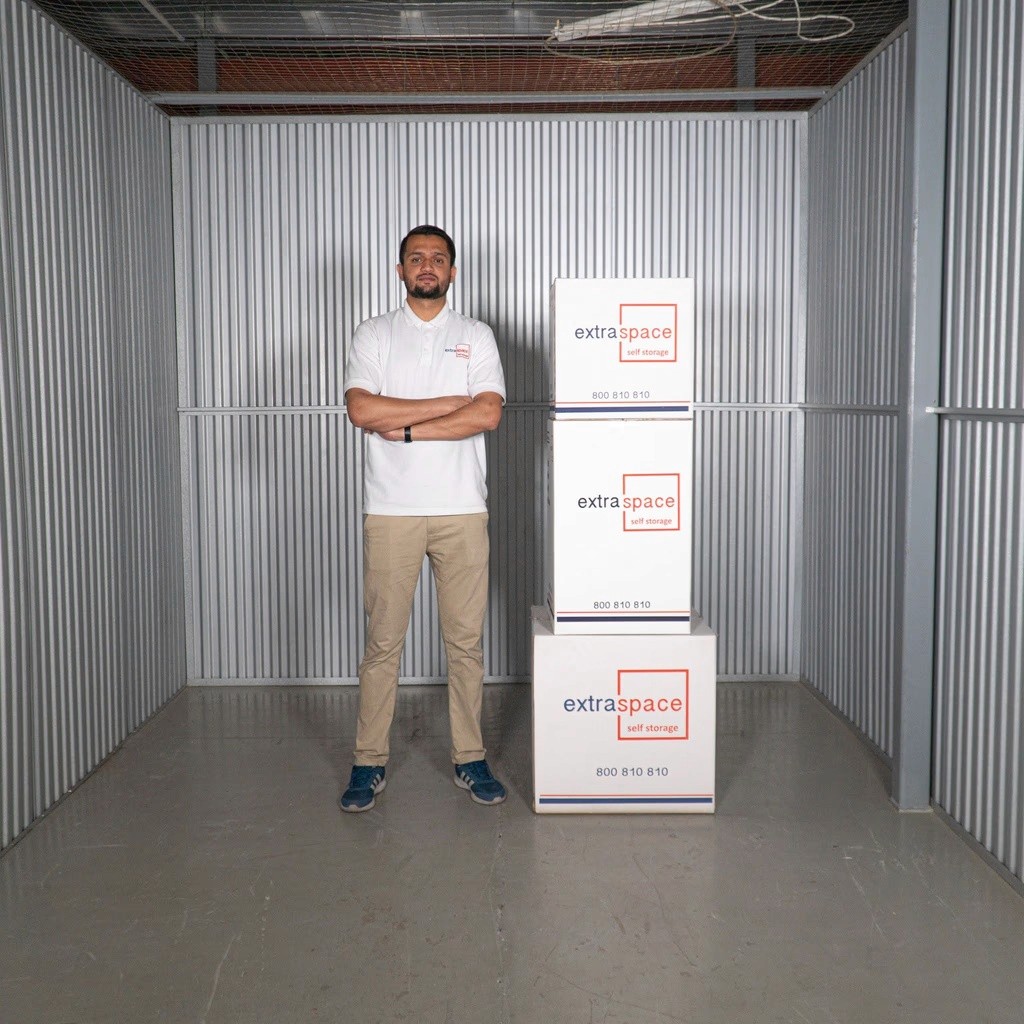 An Extra Space office mover standing next to boxes delivered to the storage unit by office movers in Dubai.
