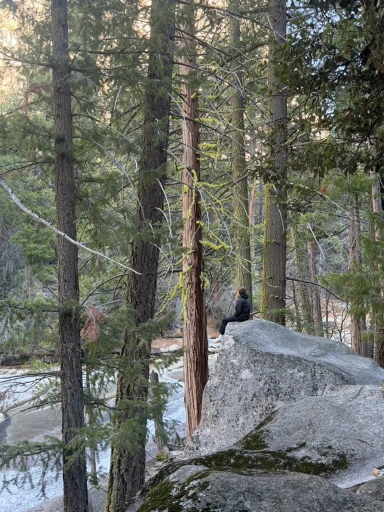 Man sitting in a dimly lit room, wearing a beige shirt and looking contemplative.