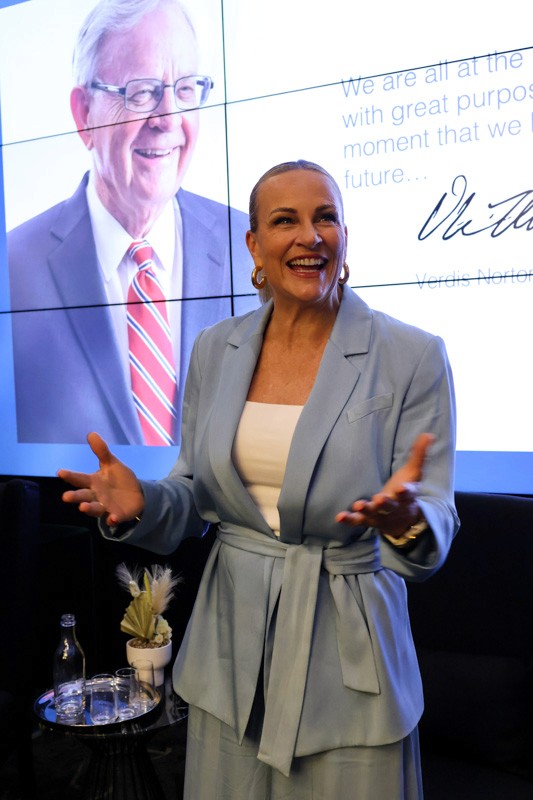 woman in blue suit stands in front of a presentation