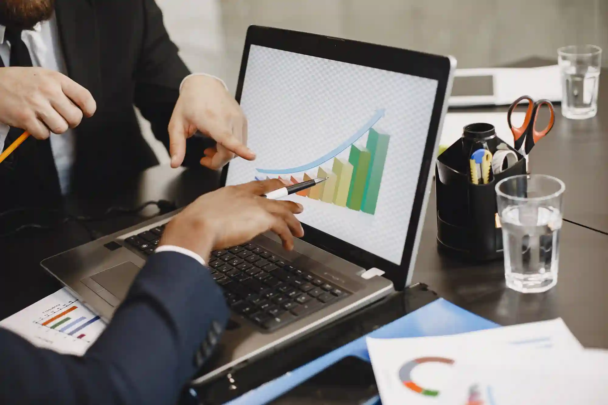 Diverse team collaborating on a project, viewing financial statistics and marketing data on a tablet device.