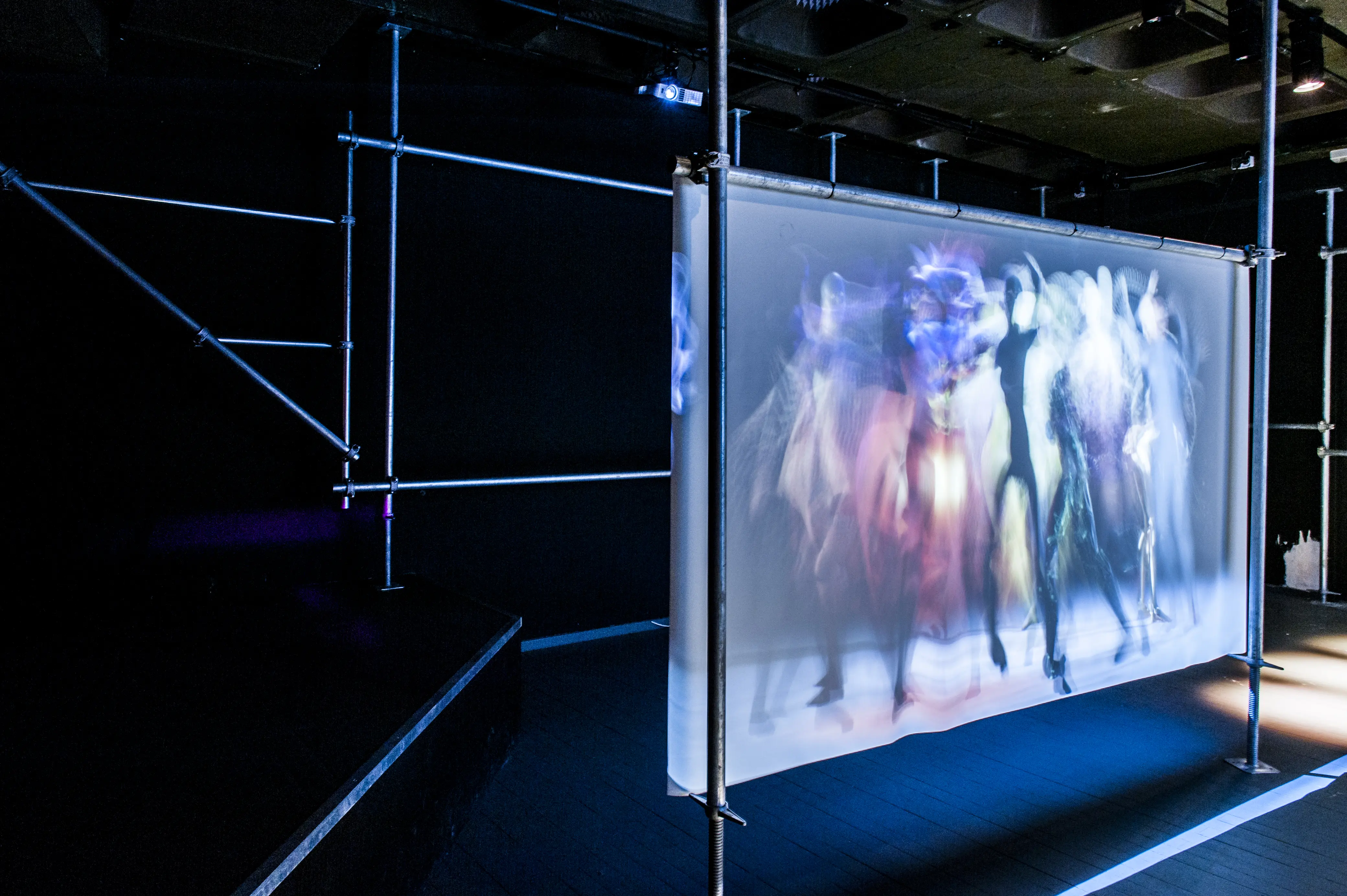 Projection of blurred dancing figures on a translucent screen mounted in a scaffolding frame at the Night Embassy.