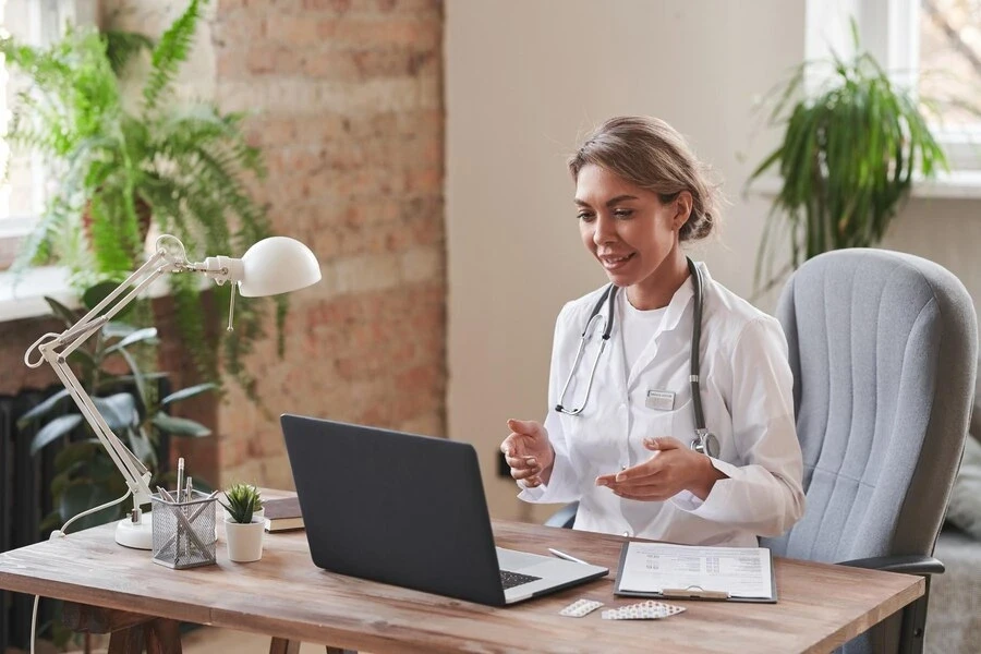 doctor-wearing-white-coat-sitting-desk-loft-office-talking-patient-video