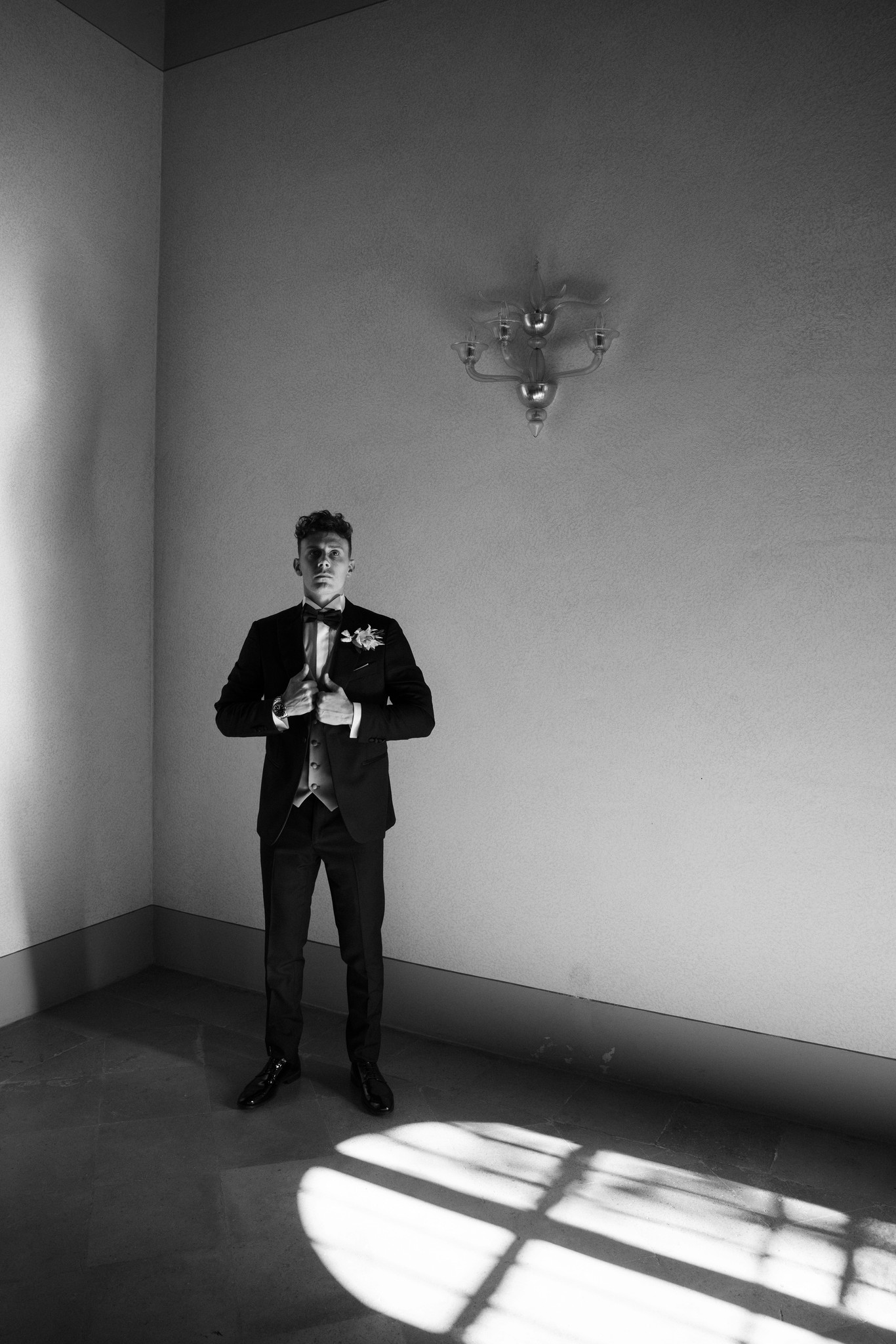 Sposo in smoking con fiori bianchi in una sala luminosa di Villa Negri, reportage di matrimonio