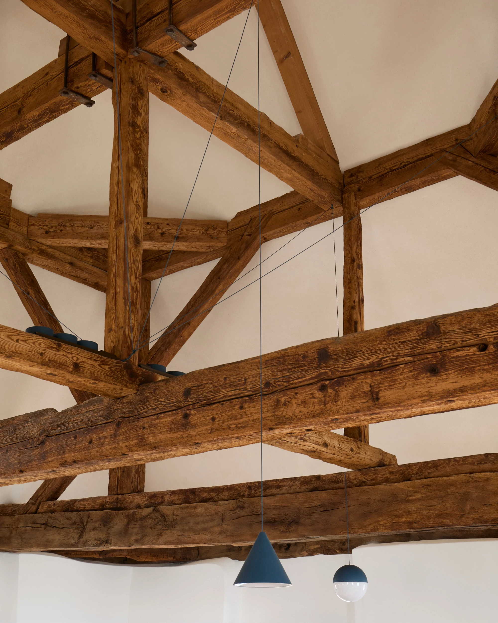 Charpente médiévale réhabilitée de la tour du Château de Saint-Prex, avec enduits à la chaux entre poutres et éclairage contemporain valorisant la structure historique.