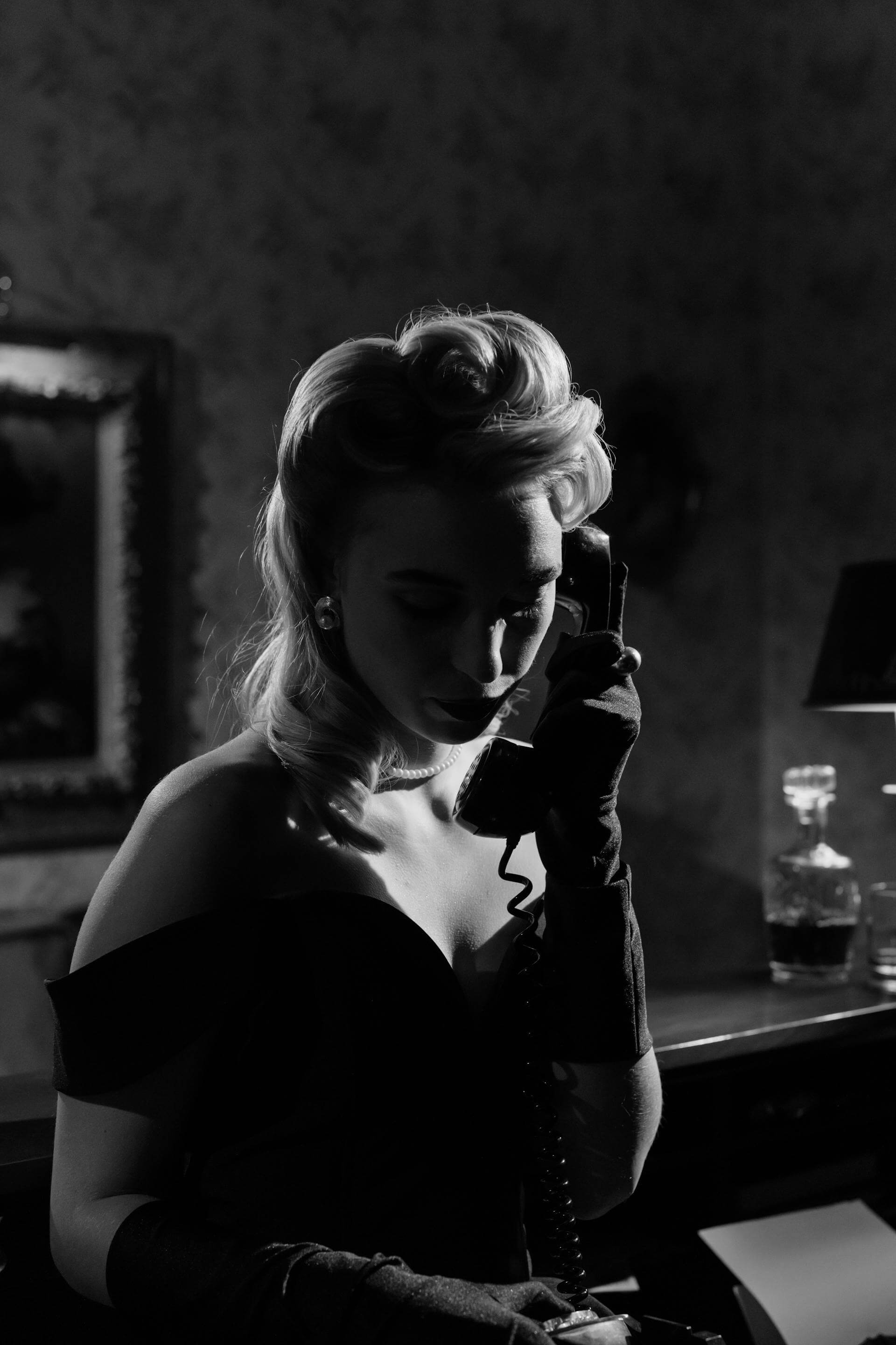 A woman in a black dress engaged in a phone conversation, exuding elegance and focus