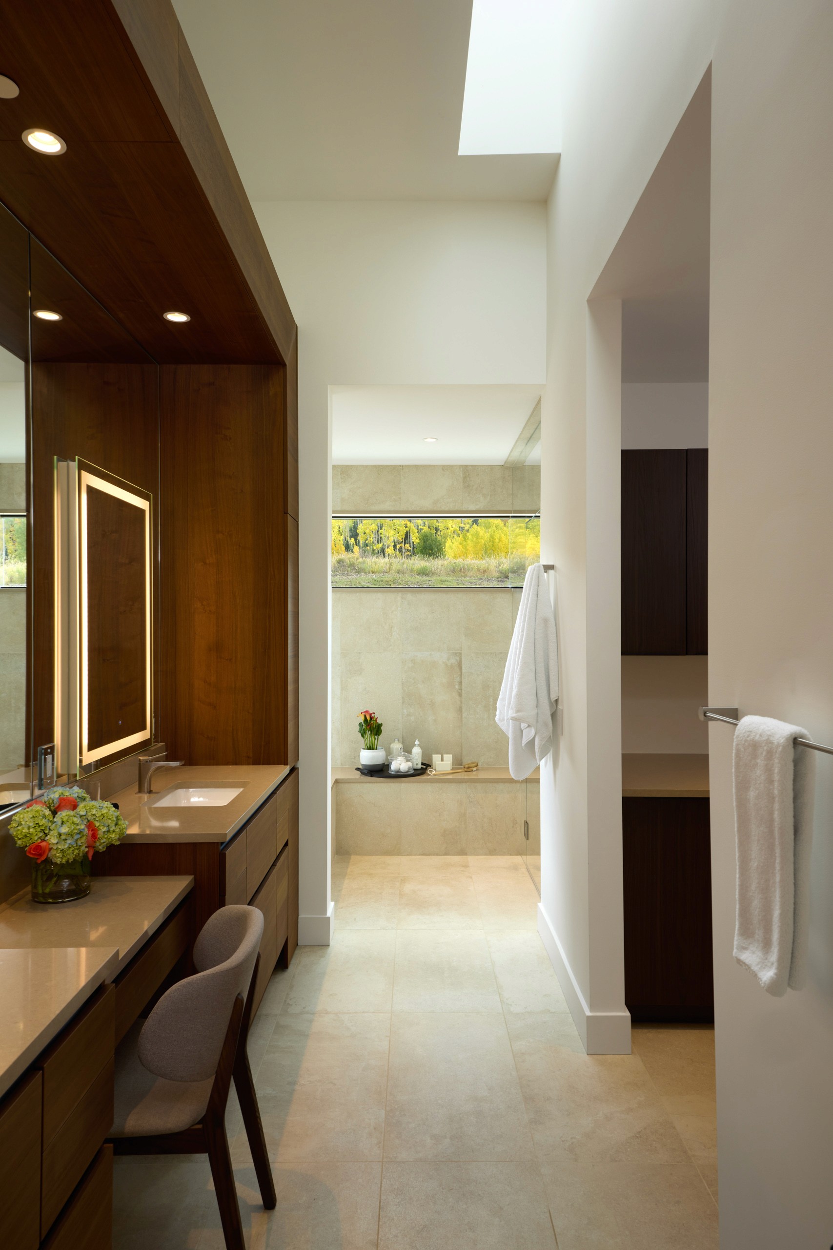 Modern bathroom with wood vanity and skylight.