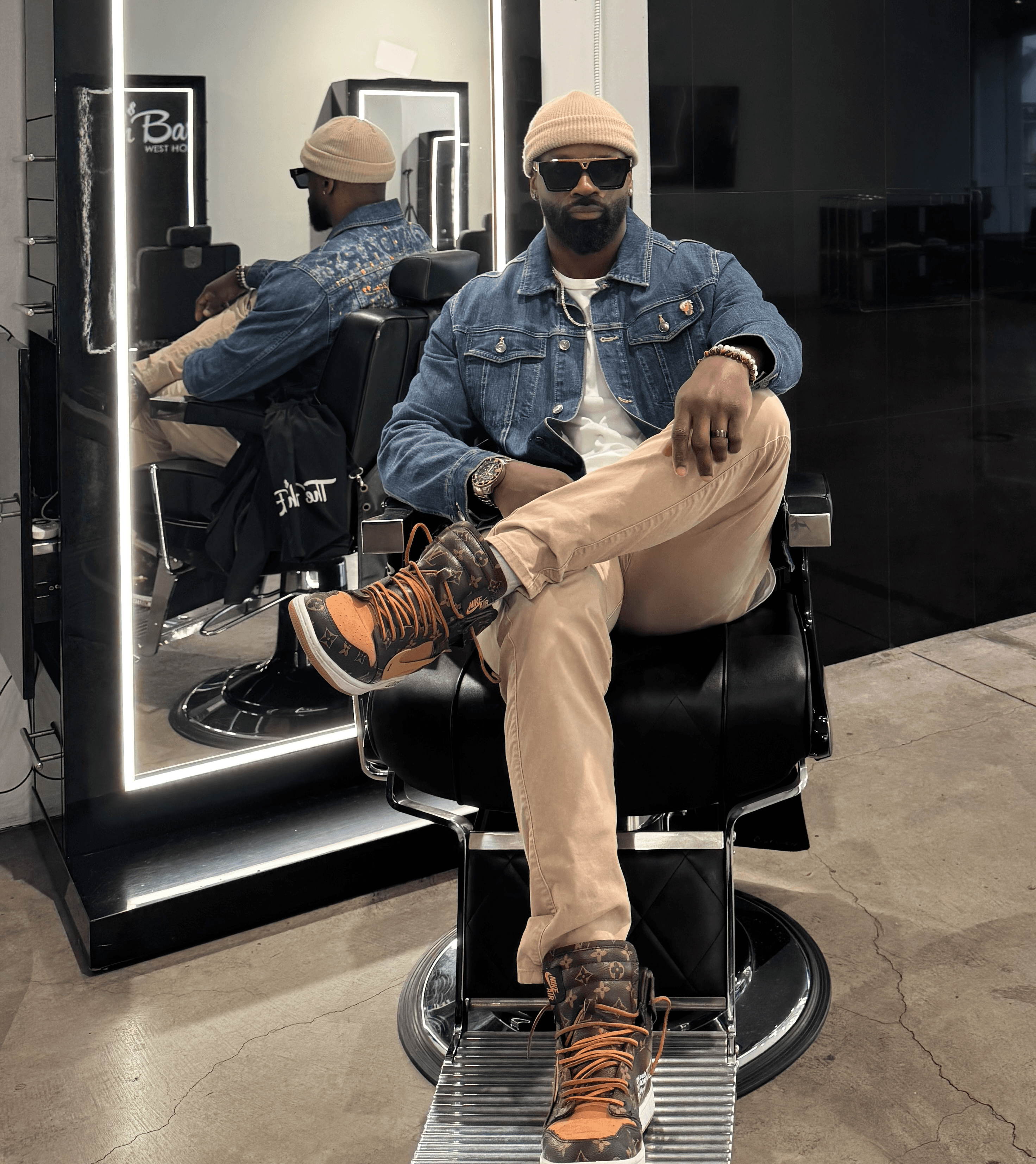 Courtney Palmore, also known as Barber.CLP, sitting confidently in a barber chair at The Rich Barber in West Hollywood, showcasing his expertise in professional grooming and luxury barbering services.
