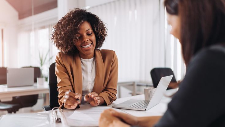 A workspace with tax forms, a calculator, a pen, an envelope, sticky notes, and a cup of coffee on a dark desk.