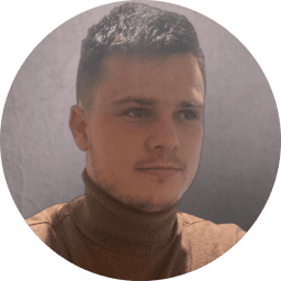 A 3D animated character with short dark hair, wearing a light blue shirt and pink tie, against a light blue background.