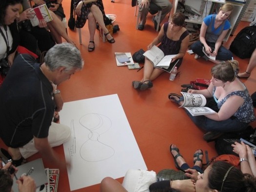 A photo of a person showing a drawing to a group of students.
