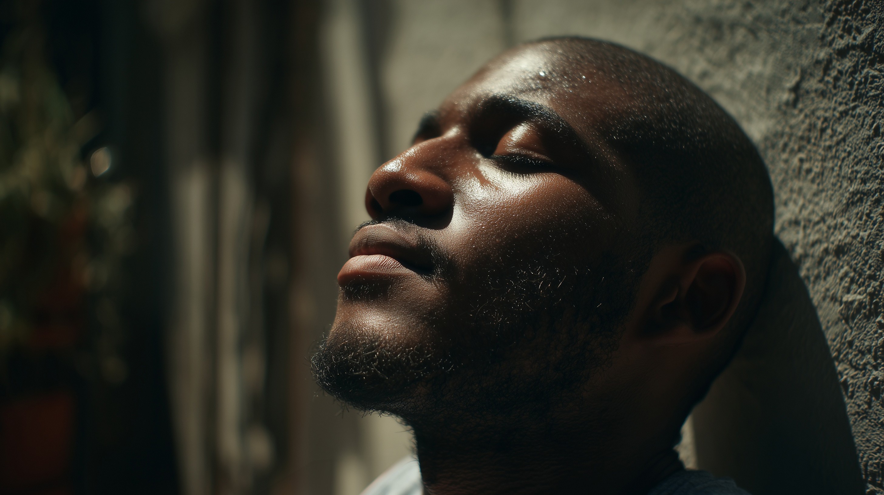 Cinematic AI generated close-up portrait of a man with eyes closed, illuminated by warm sunlight against a textured wall.