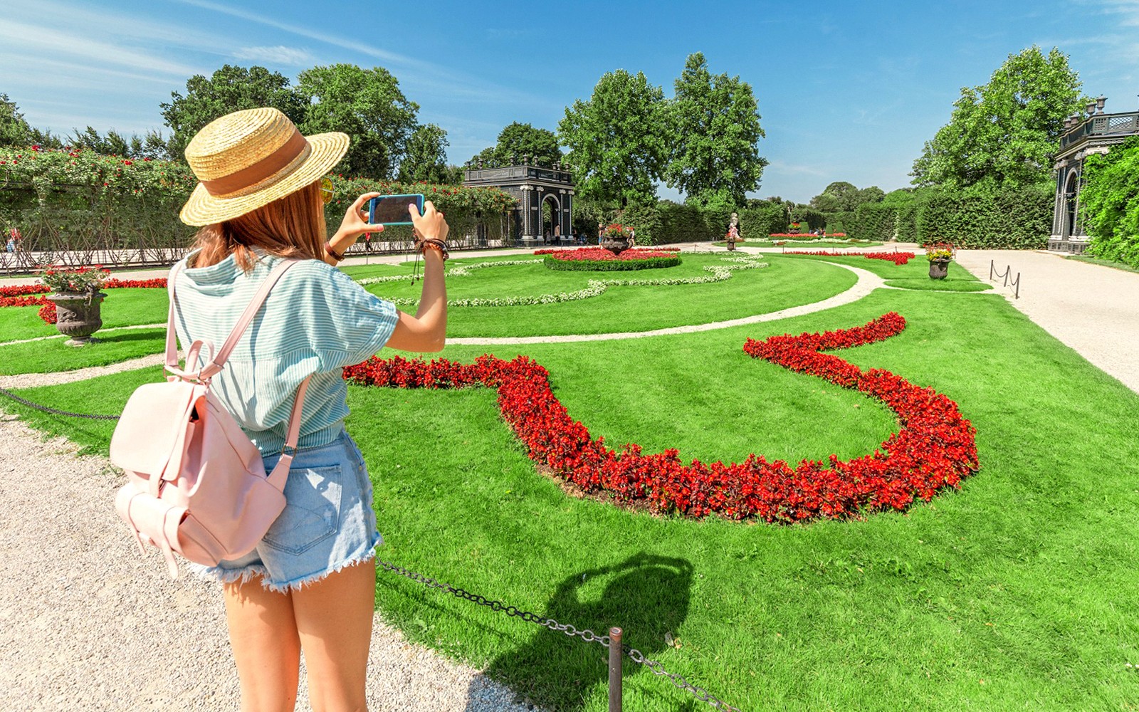 Wisatawan mengambil foto Taman Istana Schönbrunn, Wina, dengan hamparan bunga yang berwarna-warni.