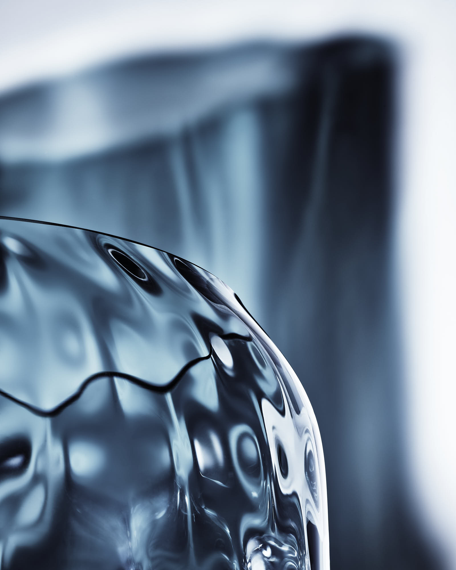 Abstract blue glass sculpture with intricate organic textures and reflections.