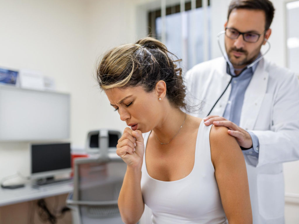 A doctor using a stethoscope to examine a woman.