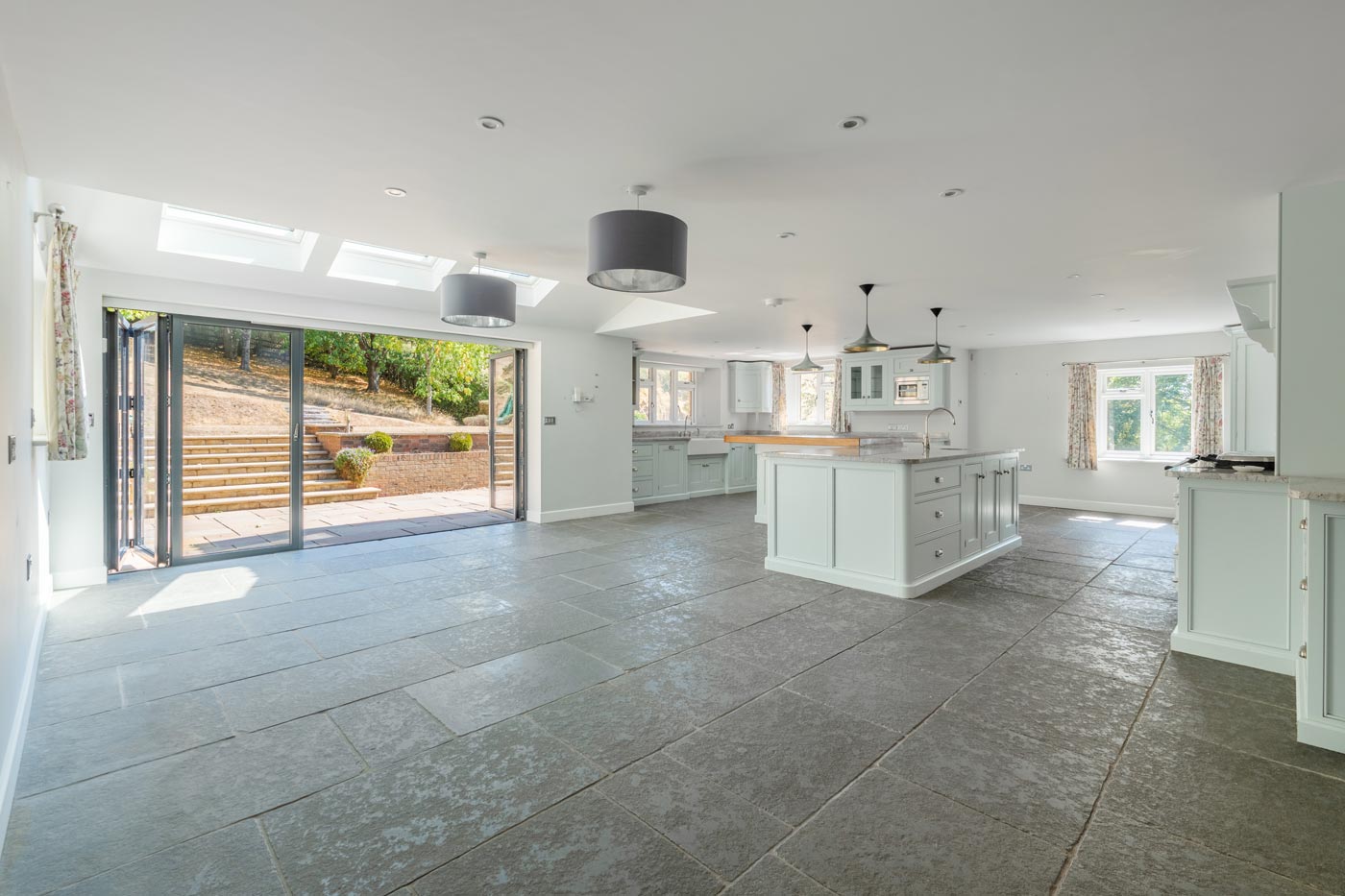open-plan kitchen with island and bi-fold doors to patioman