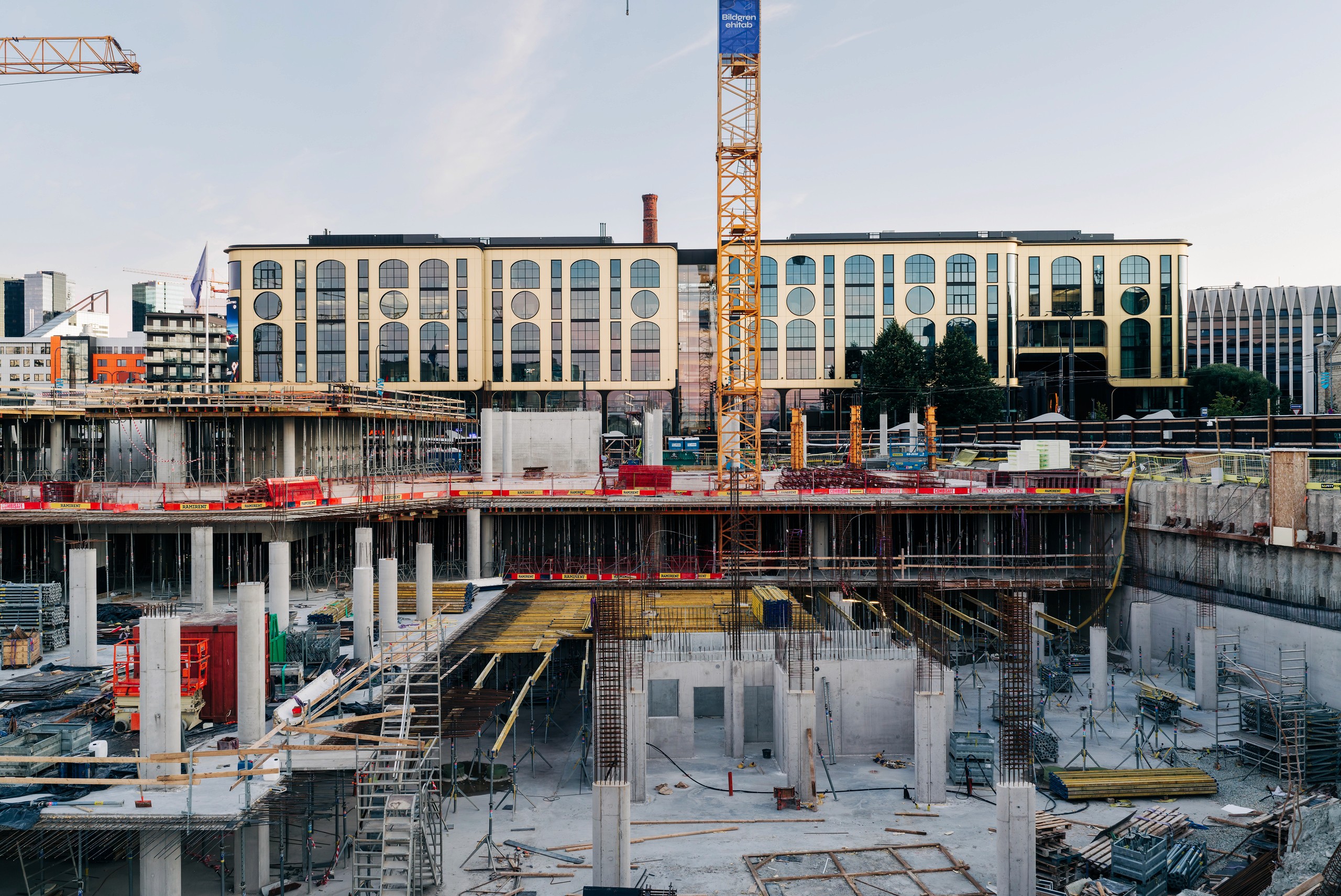 Talsinki construction progress, 18.08.2026: A frontal view shows two visible structural levels, repeated columns, walls and an upper deck edge with cranes above.
