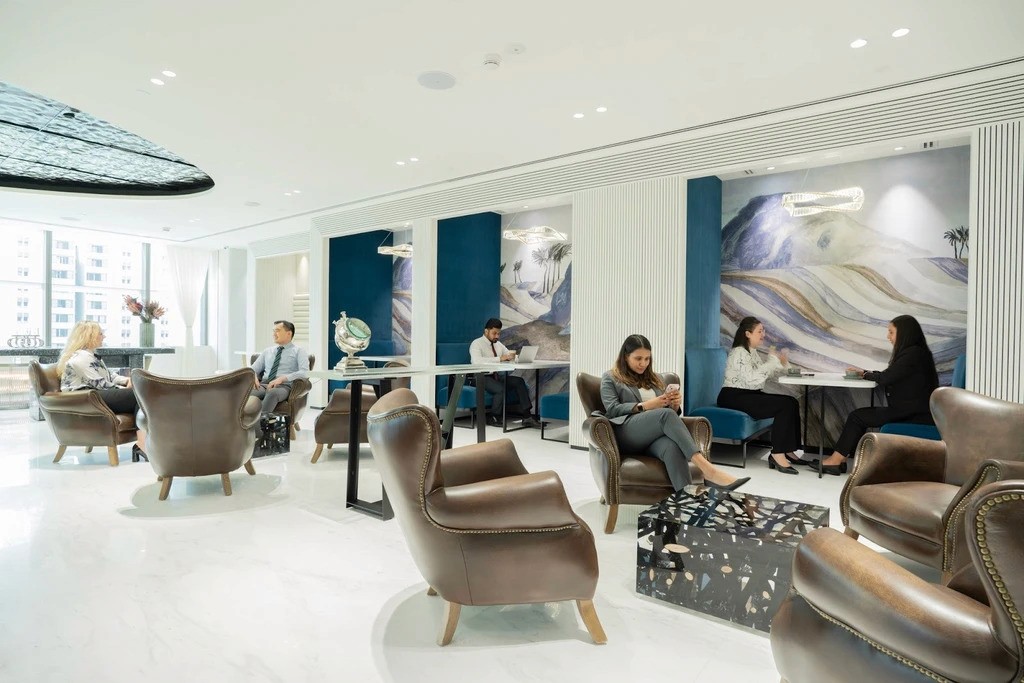 لاونج مكتب عصري يضم مقاعد جلدية وكبائن شبه خاصة مع لوحات تجريدية، مساحة واسعة ومضيئة مثالية لعقد اجتماعات التخطيط التي تجريها شركات تنظيم الفعاليات في دبي