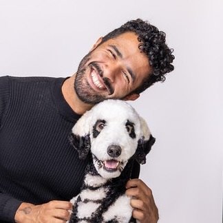 Gabriel Feitosa posing with a dog creatively groomed in a black and white panda-inspired design, expressing joy and artistry.
