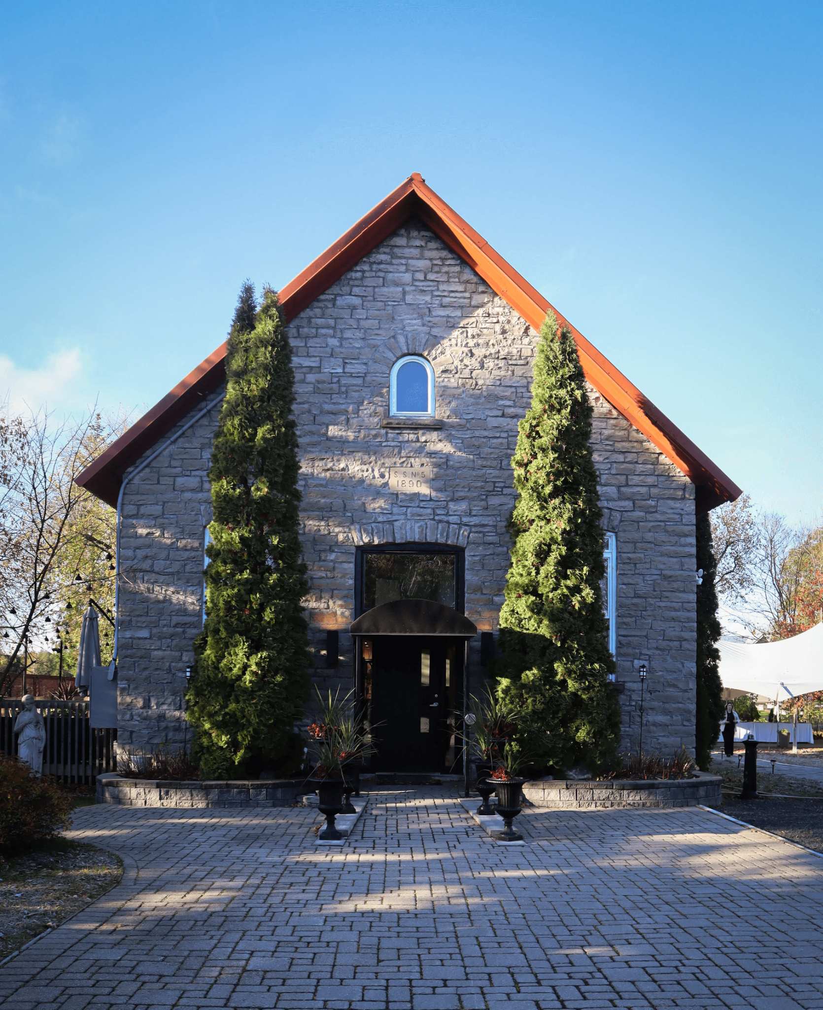 Ashlar Ottawa stone schoolhouse entrance with iron urns and awning