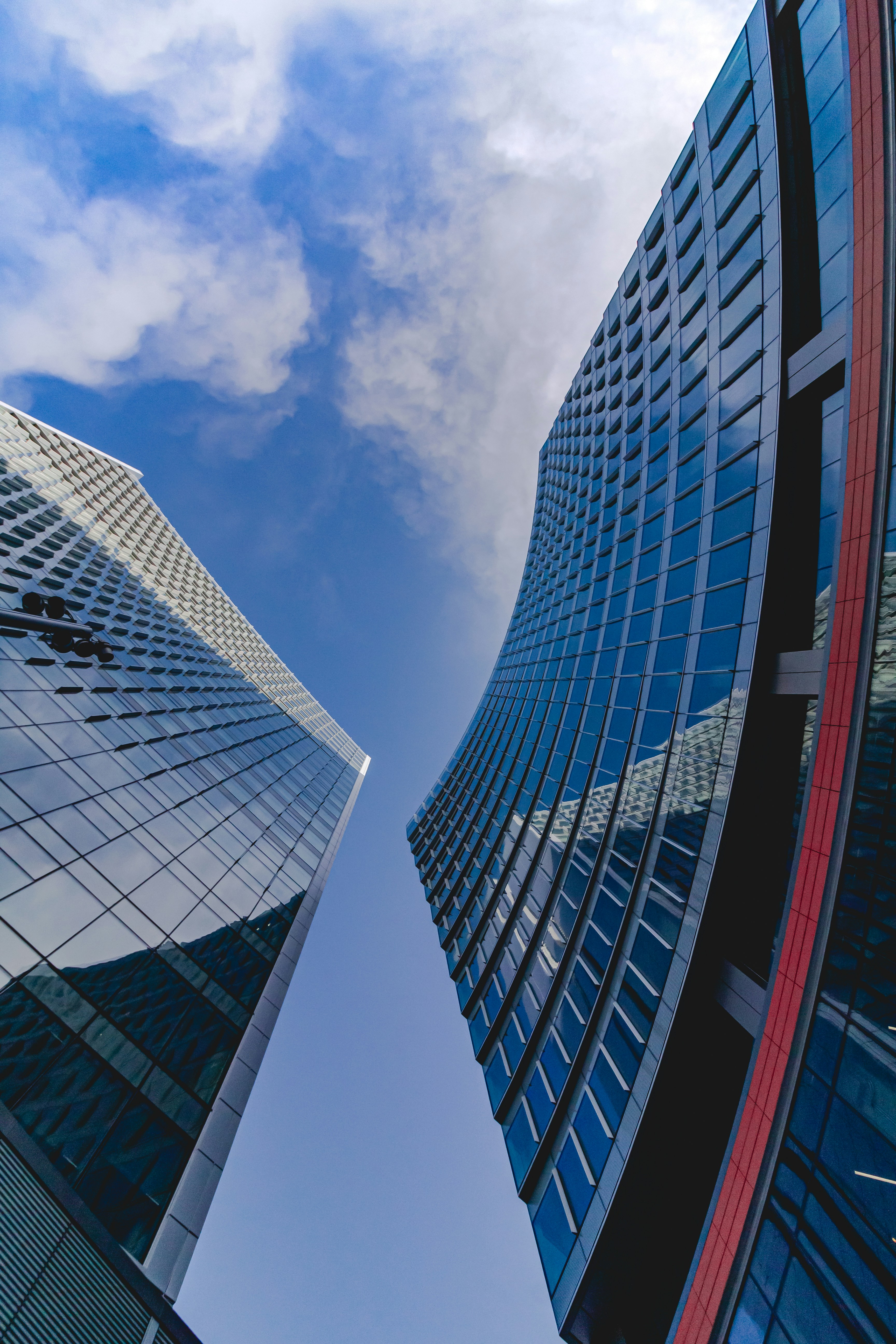 A smiling woman with her arms crossed, standing against a dark green background. She has long, dark hair.