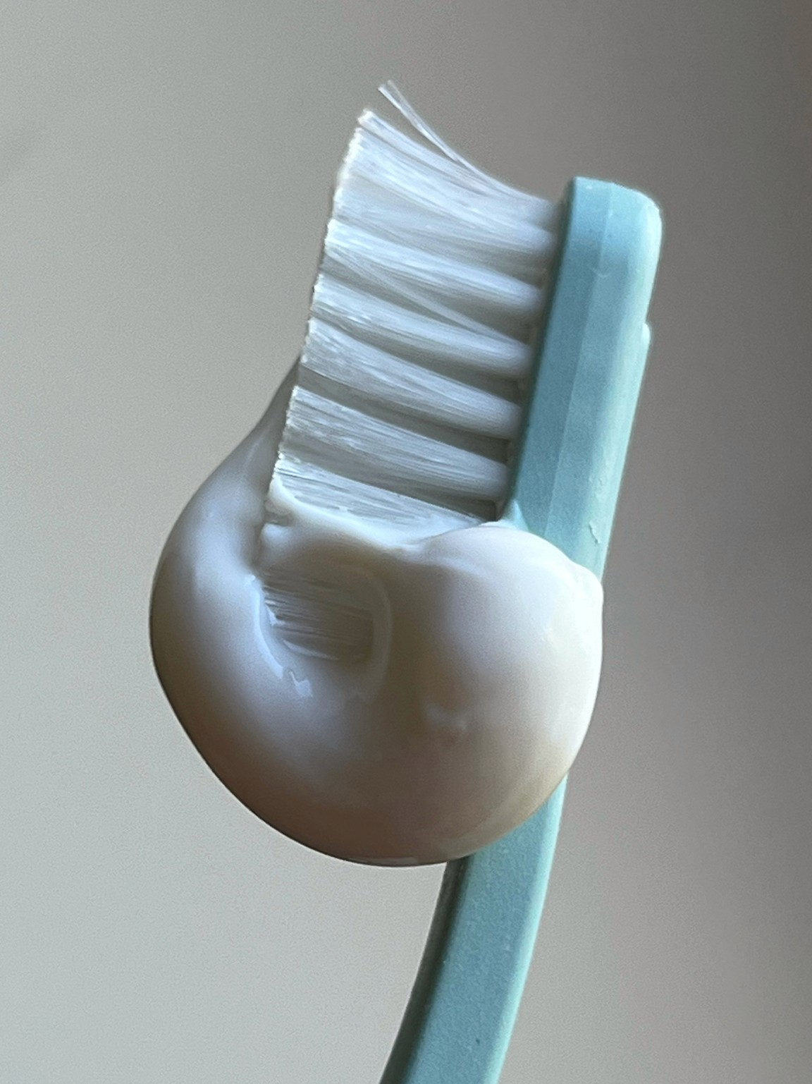 "Toothbrush head upright with toothpaste spiraled on top"