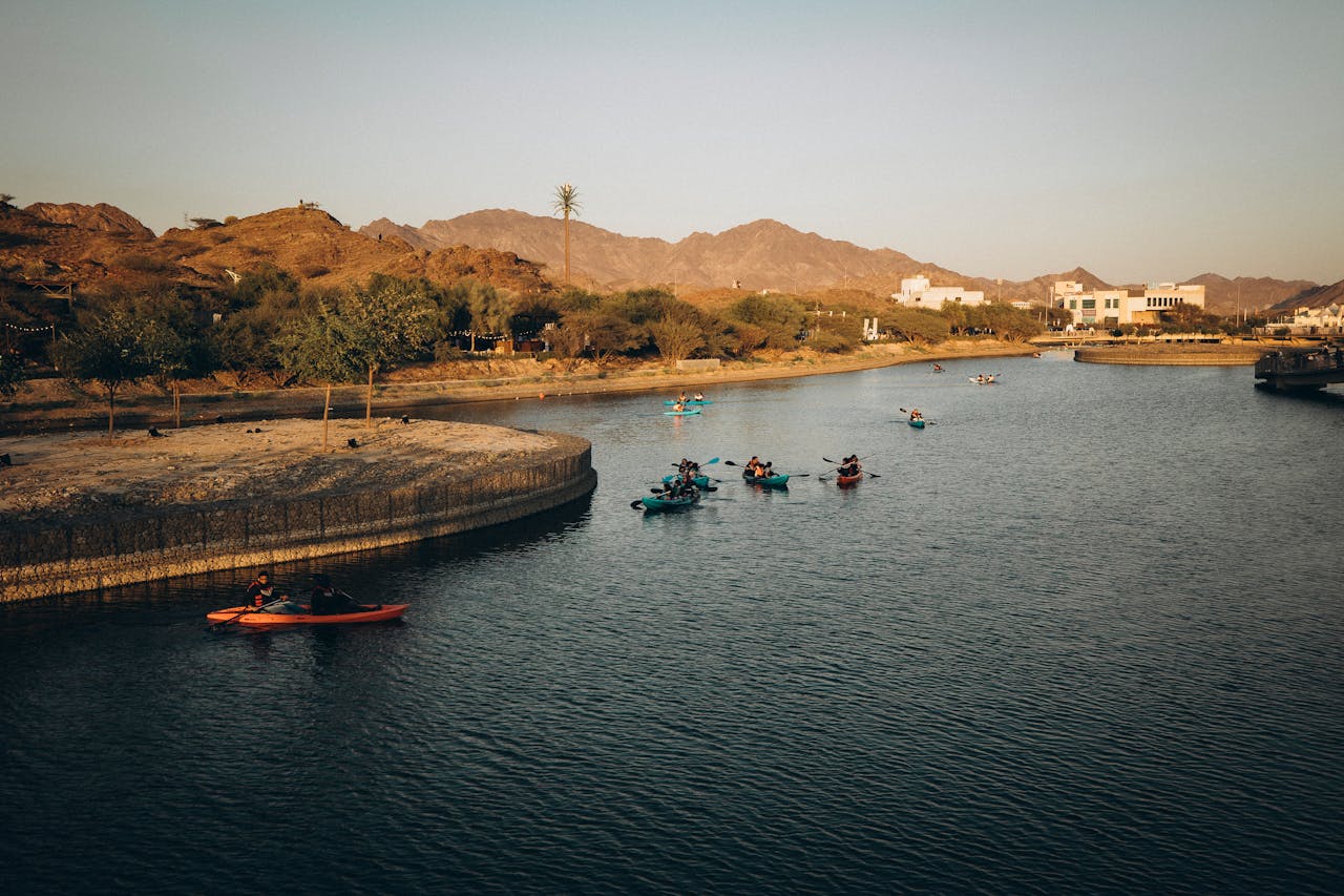 An aerial view of Hatta Dam with people kayaking, surrounded by trees and buildings, during things to do in Dubai with family.