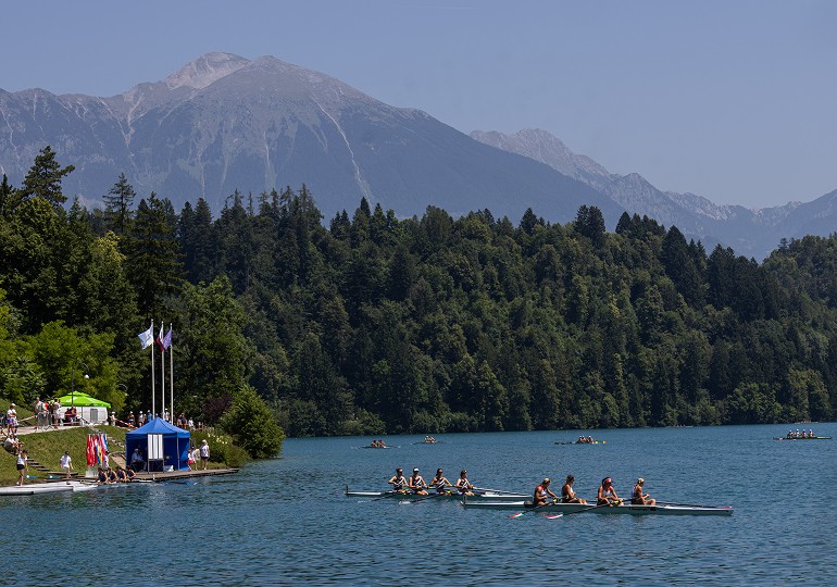 Veslařský tým trénující na jezeře pod horami
