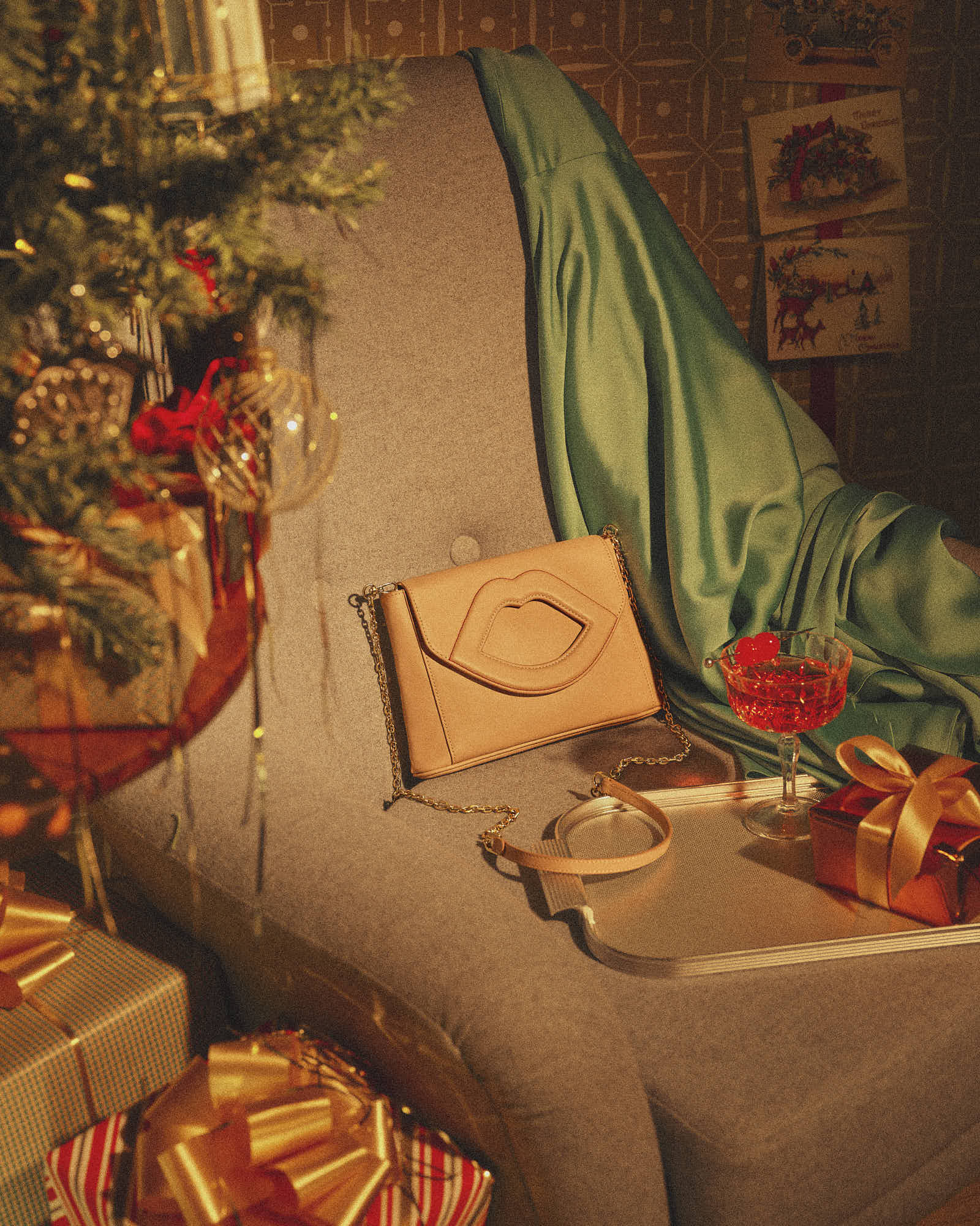 Christmas gifts and fashionable purse on chair with holiday decorations.