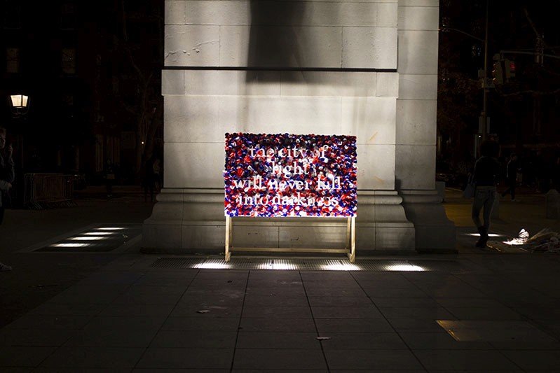 An illuminated and colorful street poster with text on it near a building.