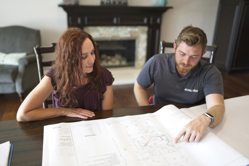 Customer and Pacific Coast Builders, Inc. employee going over construction plans in her home for her project.