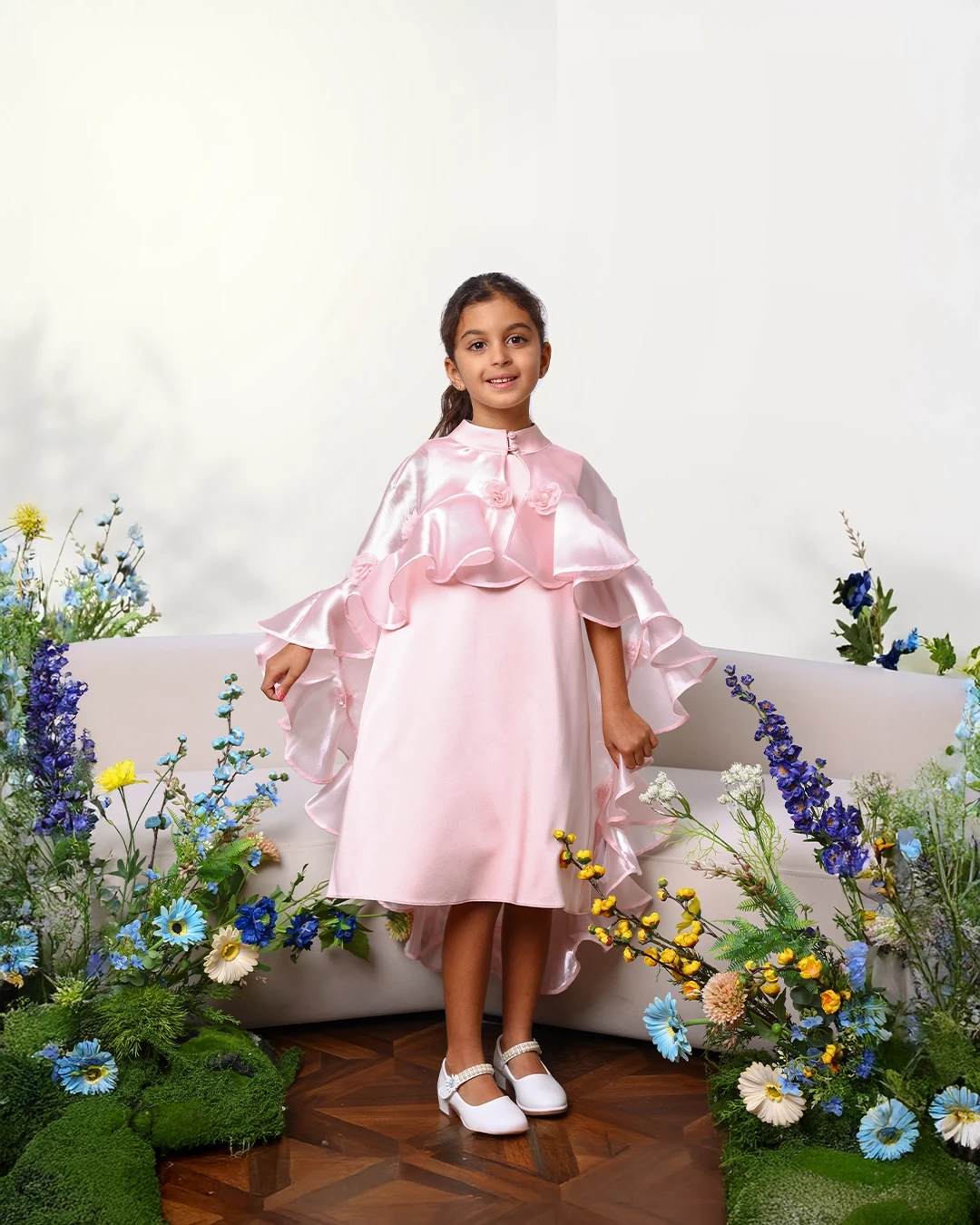 Close-up of hands adjusting green, cream, and orange Trailblaze Runner sneakers with bold sole design, worn on a textured red track surface.