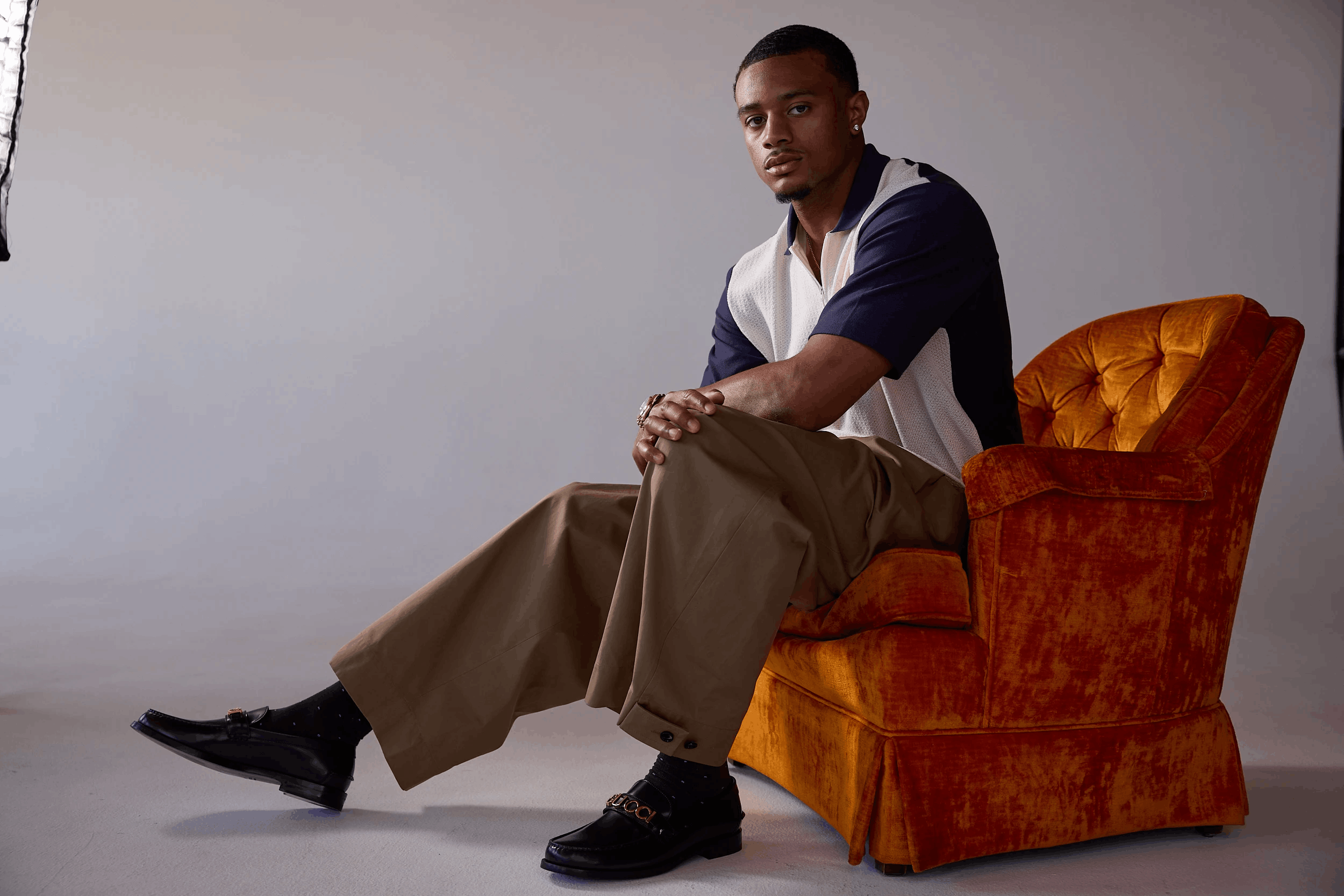 pat surtain sits on an orange chair in studio