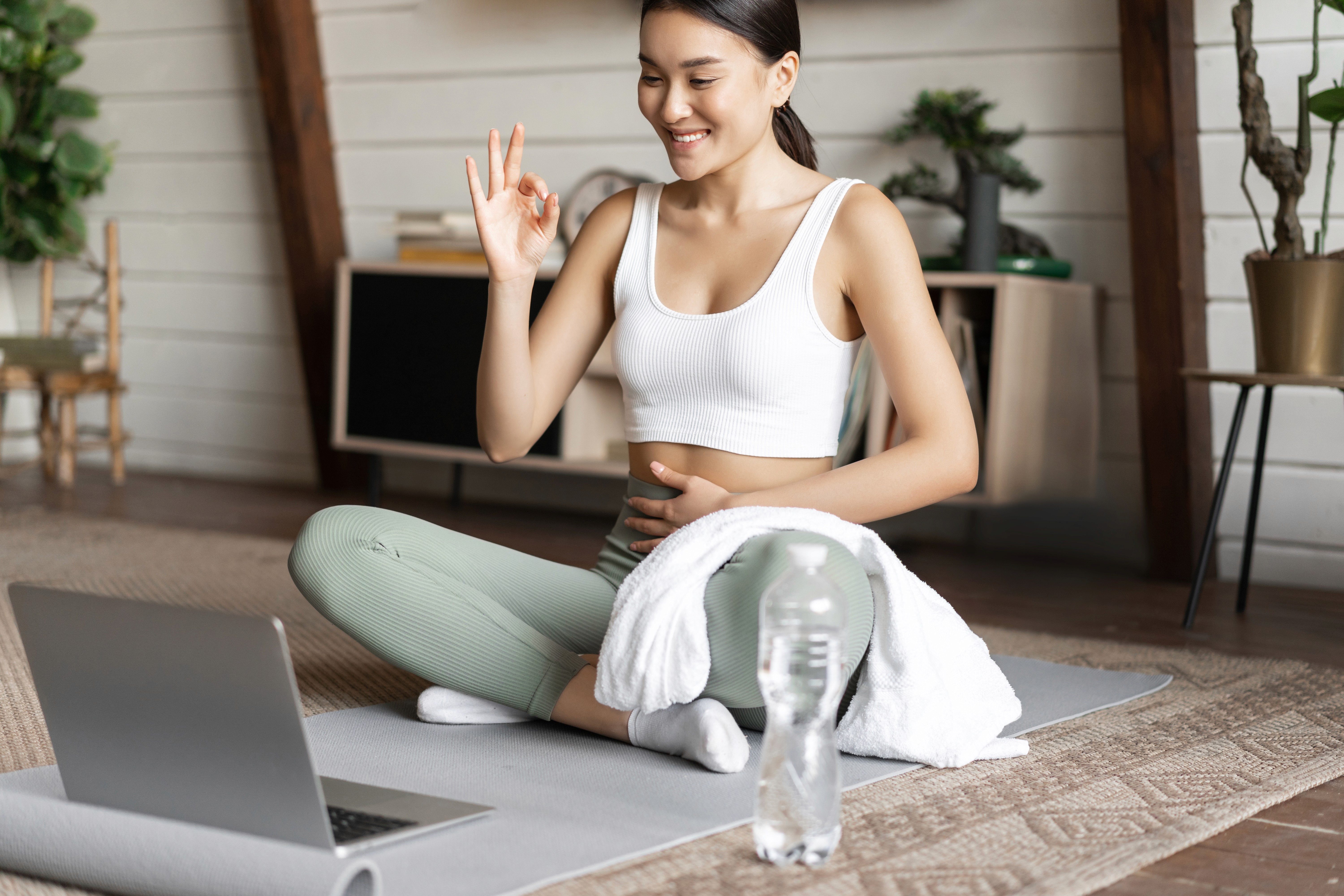A smiling young man with crossed arms, wearing a plaid shirt and white t-shirt, poses against a dark background.