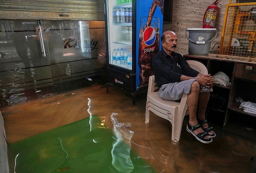 A shopkeeper watches the water level rise inside a shop during monsoon rains in Mumbai, July 4, 2026.