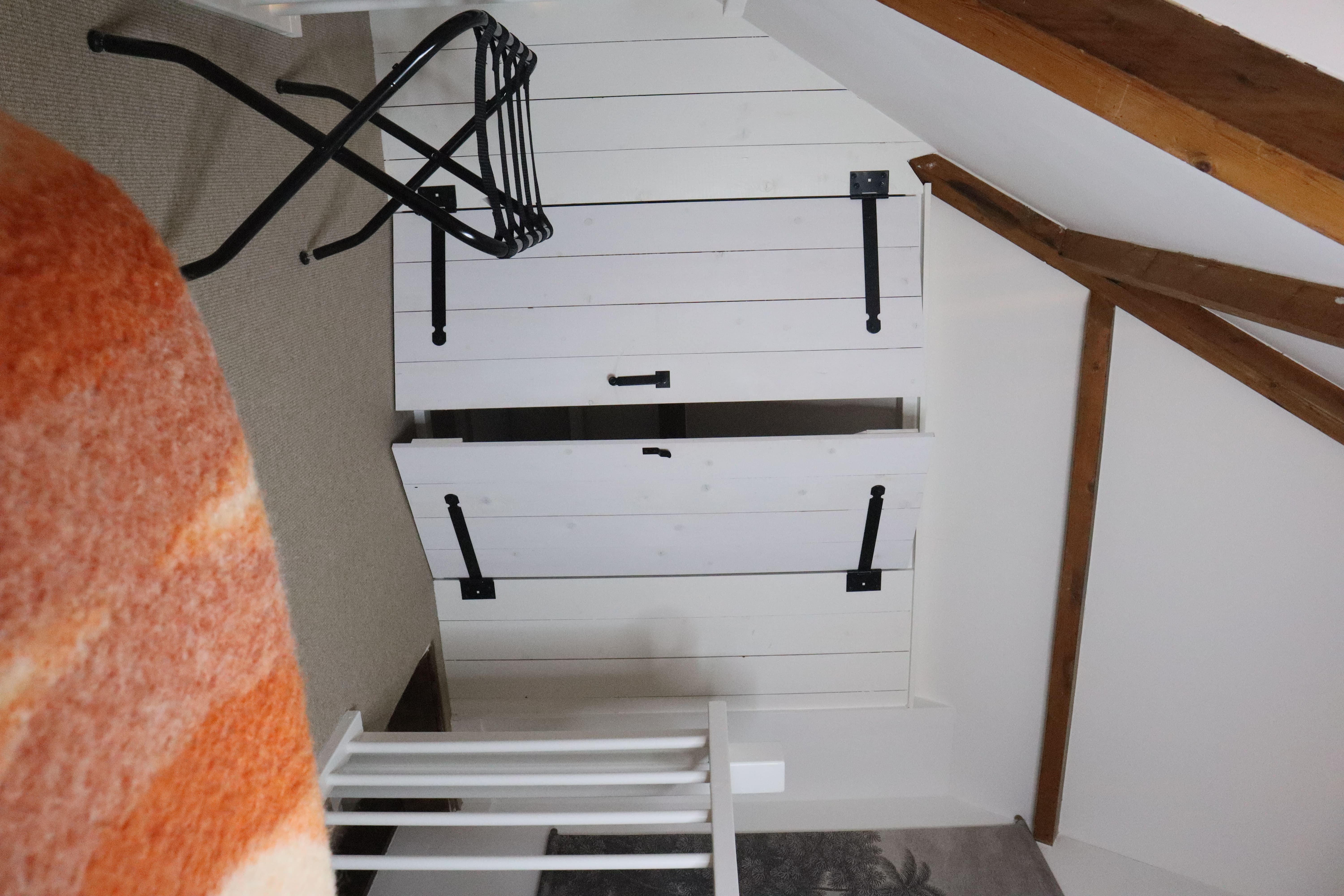 Witte kastdeuren met zwarte handgrepen, met daarnaast een stoel en een vloerkleed.