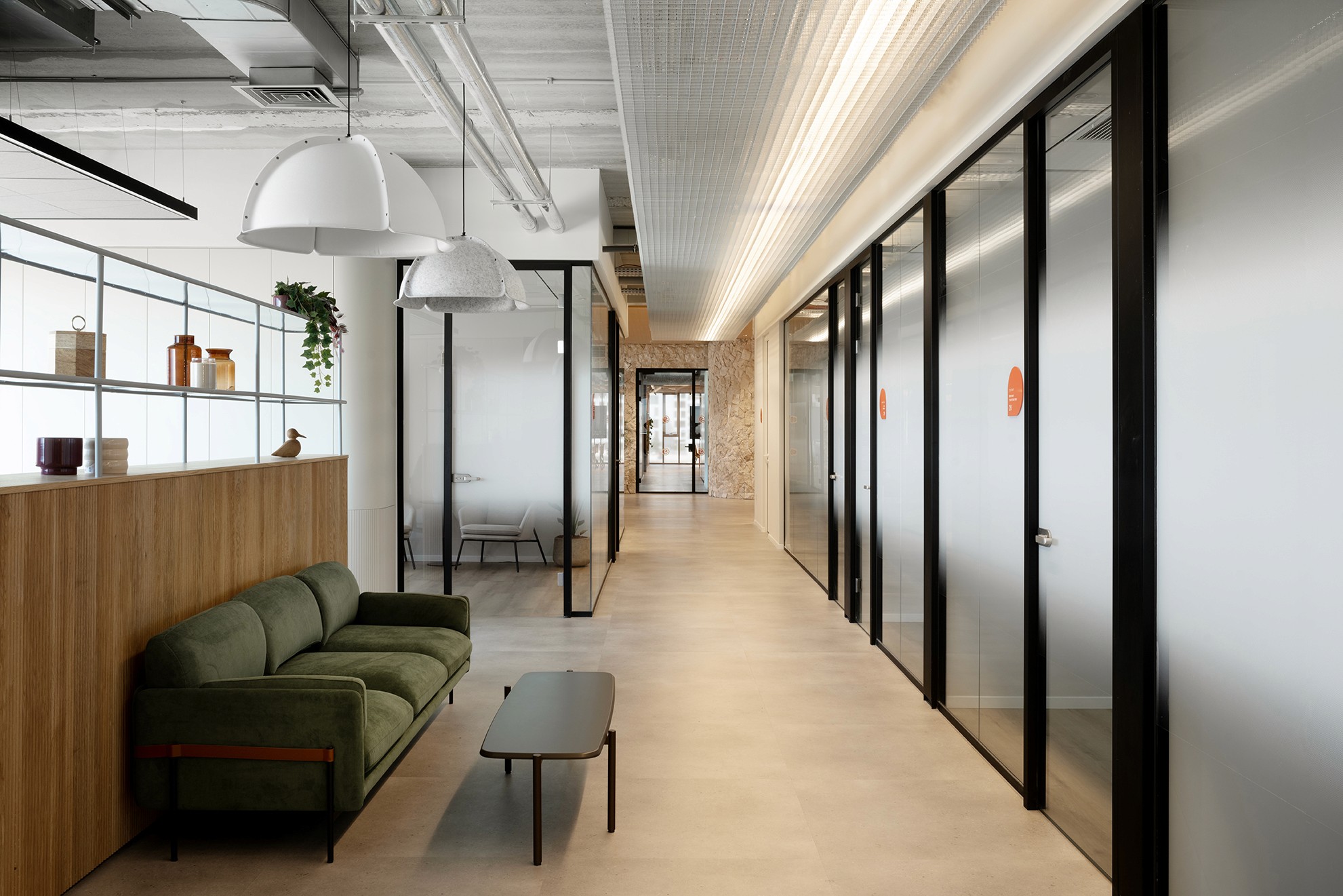 תכנון מעברים במשרד: שילוב מחיצות זכוכית עם נישות ישיבה מרופדות (Booths) ואלמנטים של נגרות אדריכלית