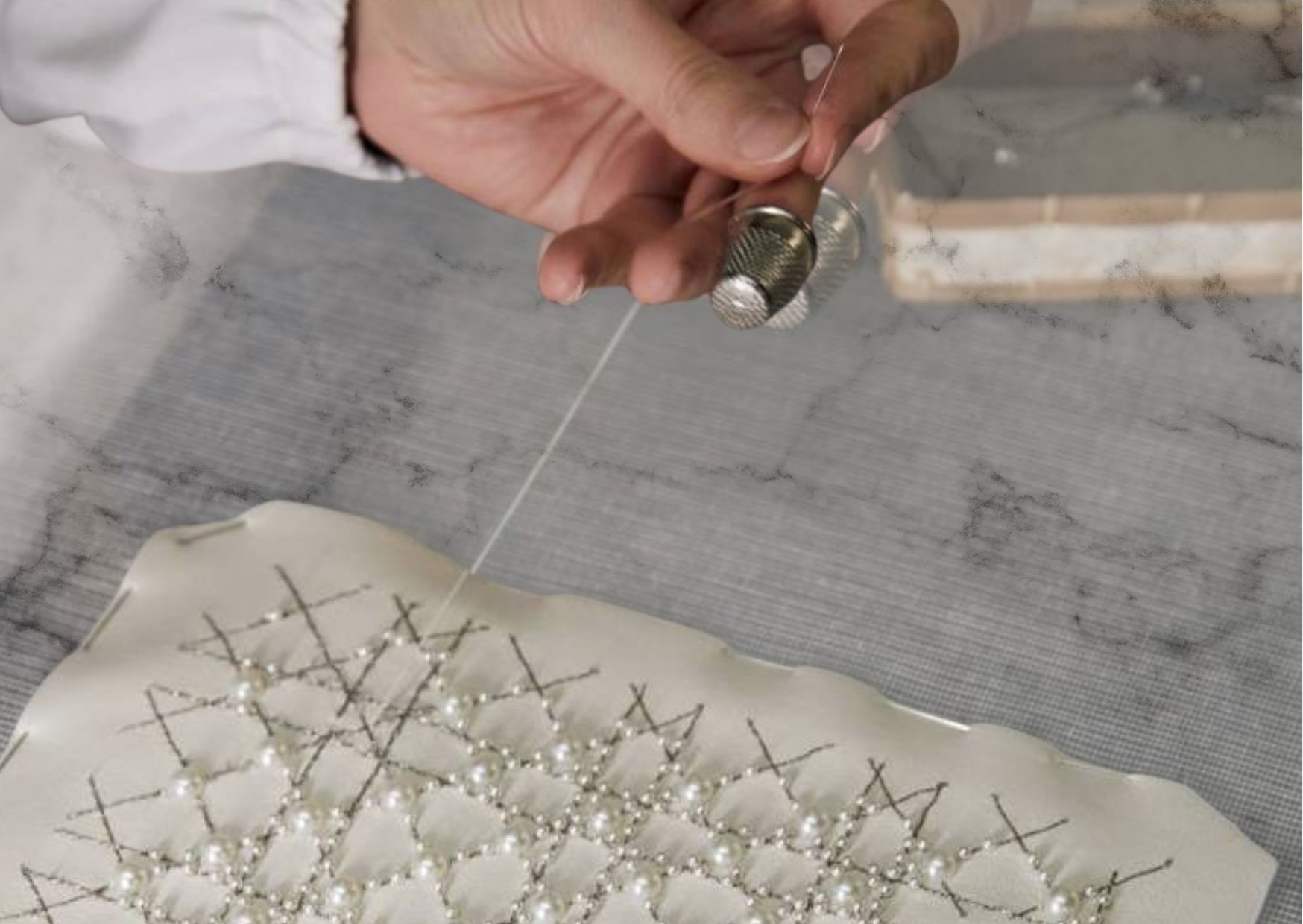 A skilled artisan delicately crafts the Lady Dior bag, stitching thread into intricate and precise pattern.  He's creating the elegance.