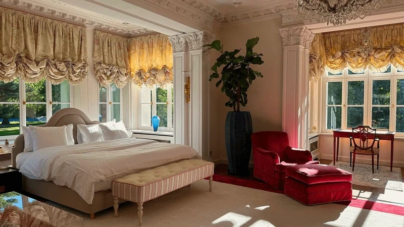 a palace bedroom with a large bed and a window overlooking the park
