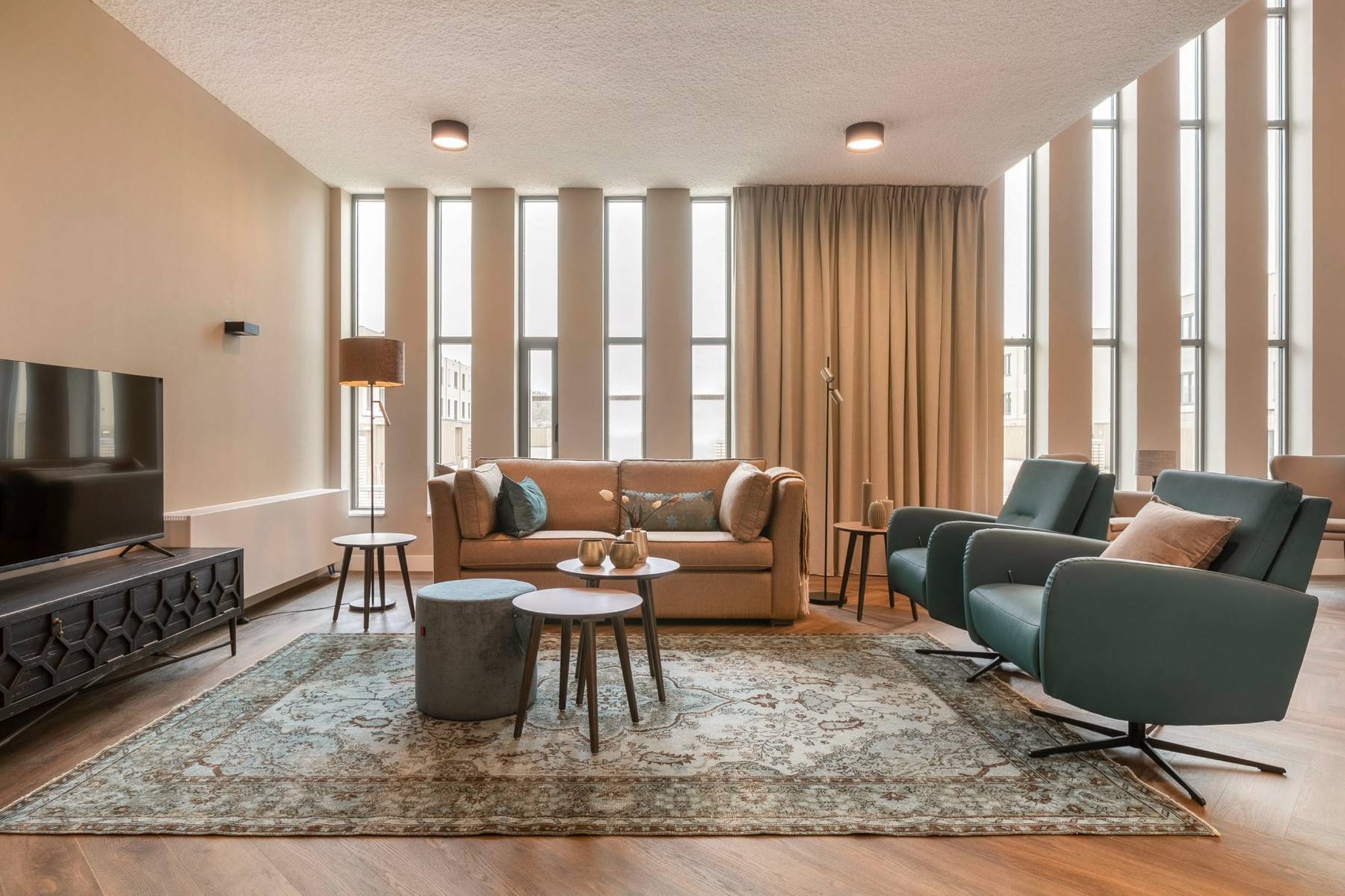 woonkamer met beige bank en blauwe fauteuils