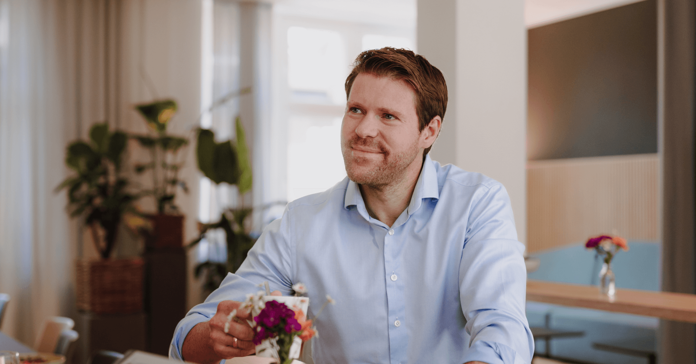 Ein Männlicher Geschäftsführer im hellen Hemd sitzt im Gespräch an einem Tisch im Büro von SLB.