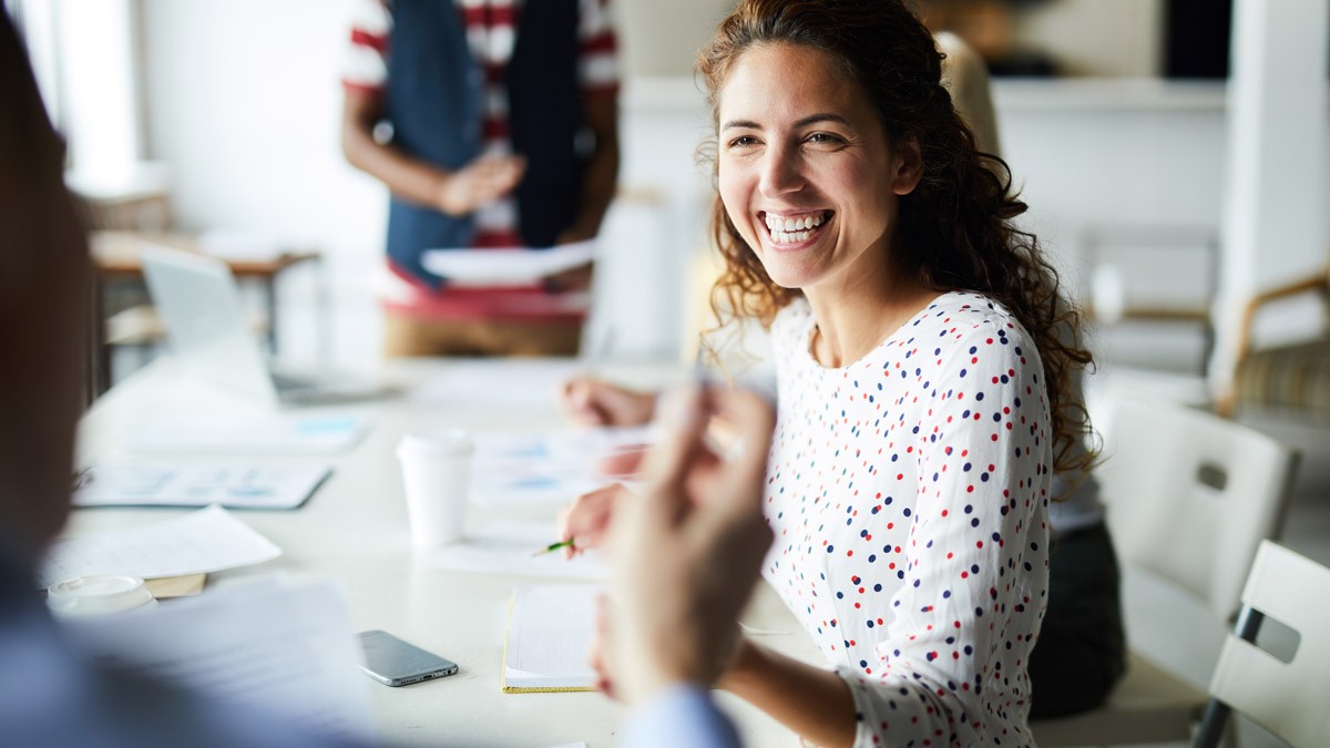 A workshop participant smiling while listening to another workshop participant.