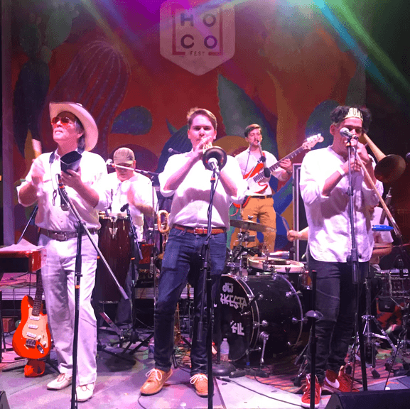 Alex playing trumpet on a stage with a larger band