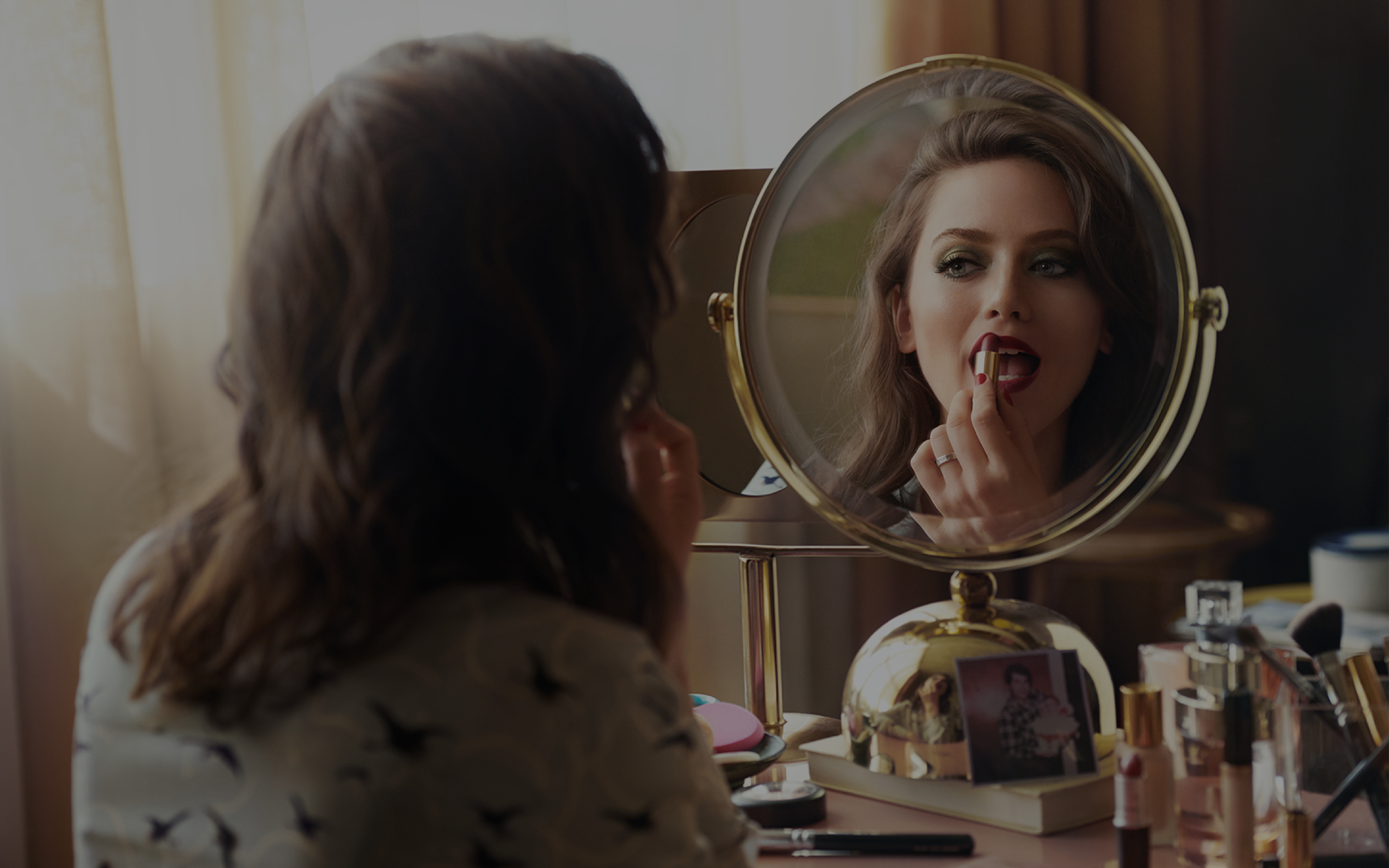 Young woman applying makeup in front of a mirror